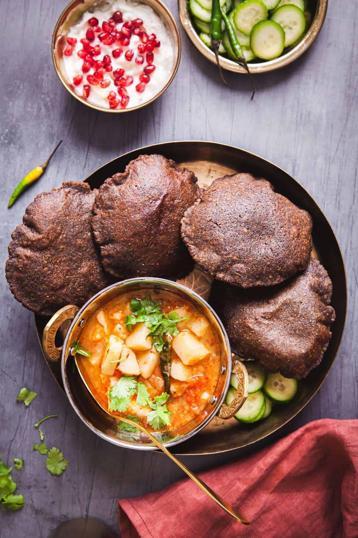 Kuttu Ki Poori With Potato Curry on a plate with yogurt and cucumbers. 