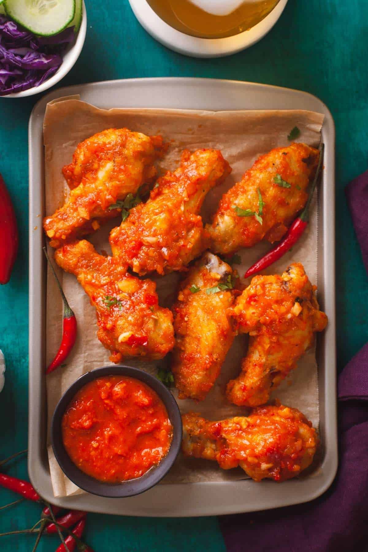 Hot Garlic Chicken Wings on a small tray with drink and raw cabbage.