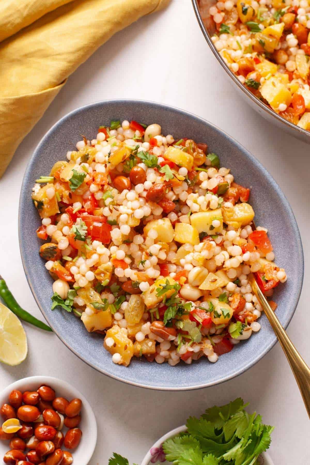 Close up of sabudana khichdi. You can see peanuts, raisins, potatoes and tomatoes.