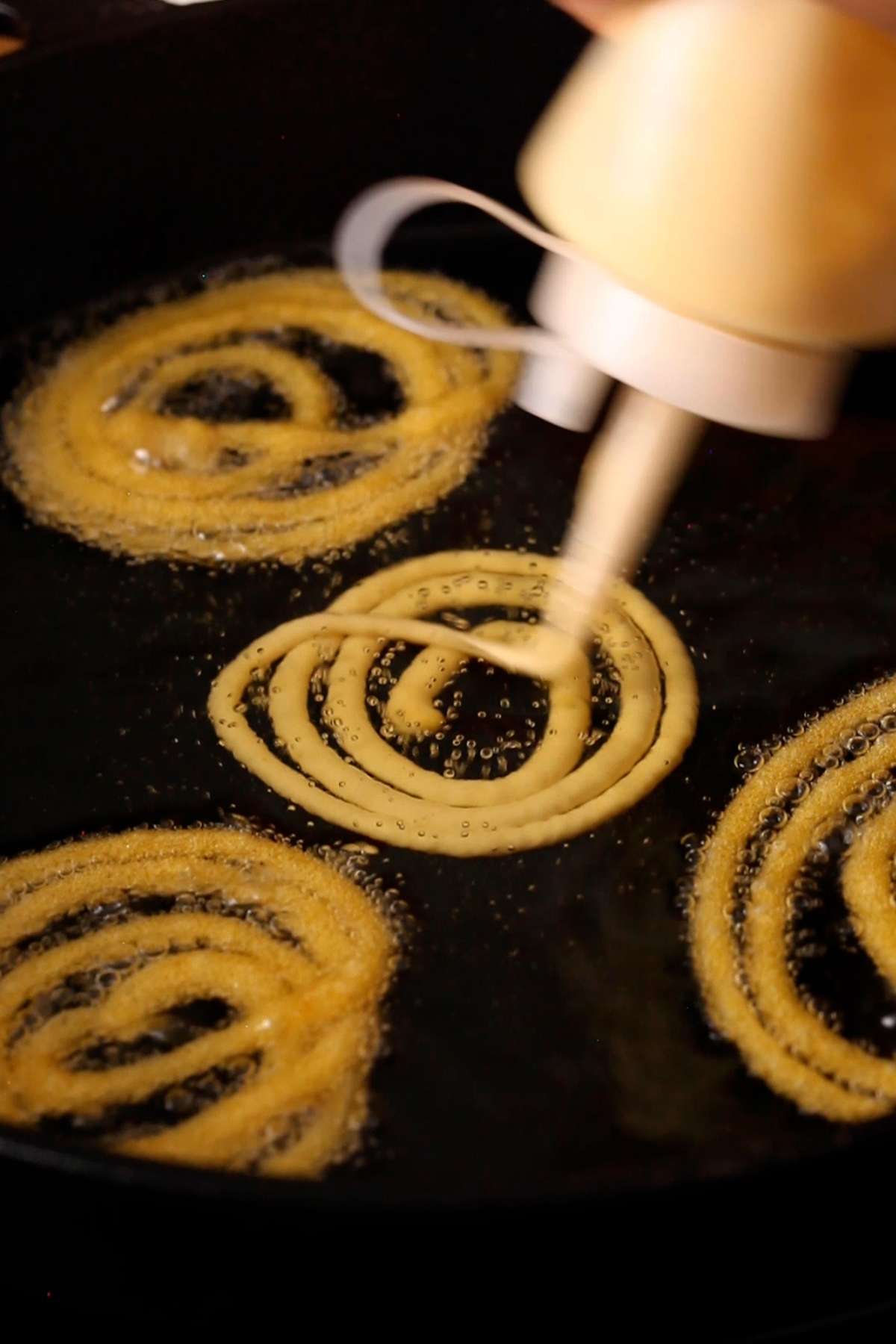 Piping jalebis into hot oil using a squeeze bottle.