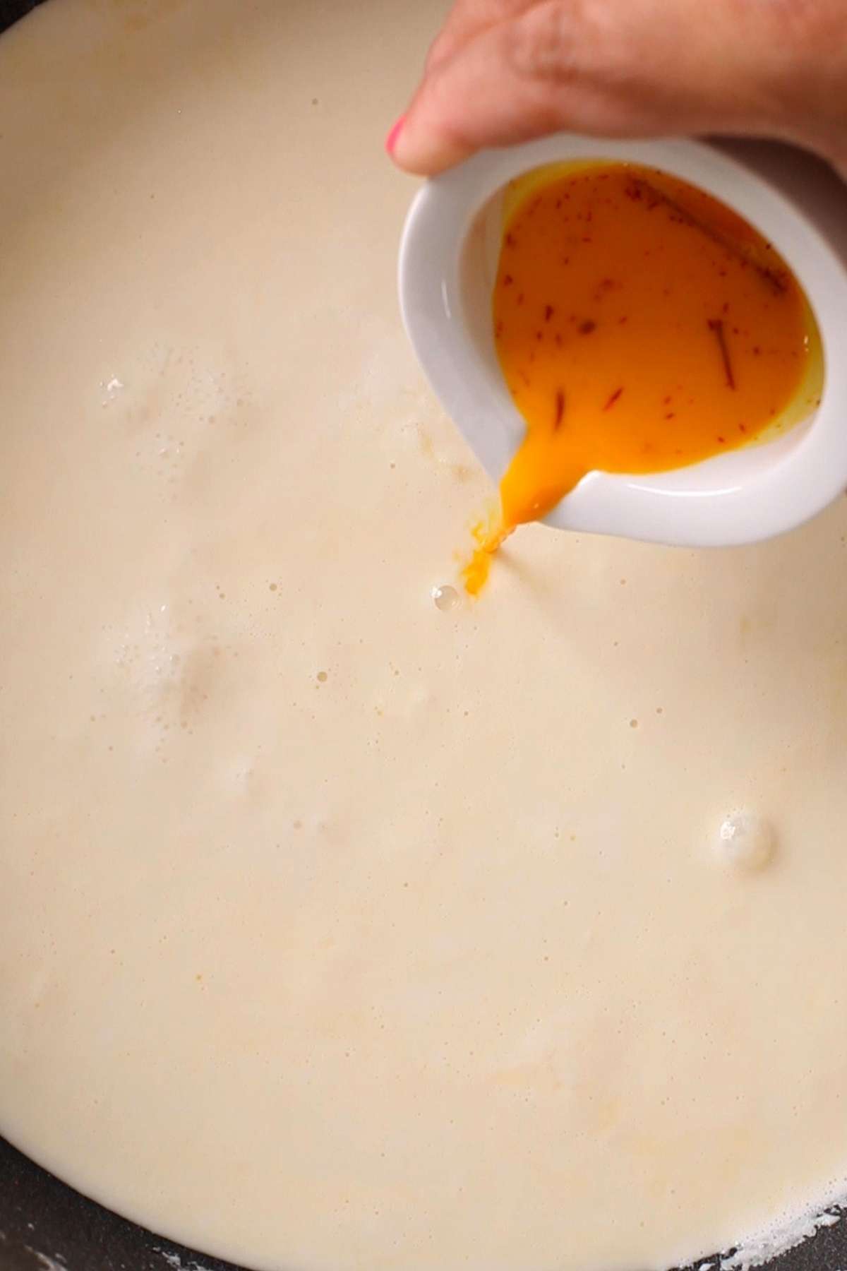 Saffron mixture being added to rabdi.