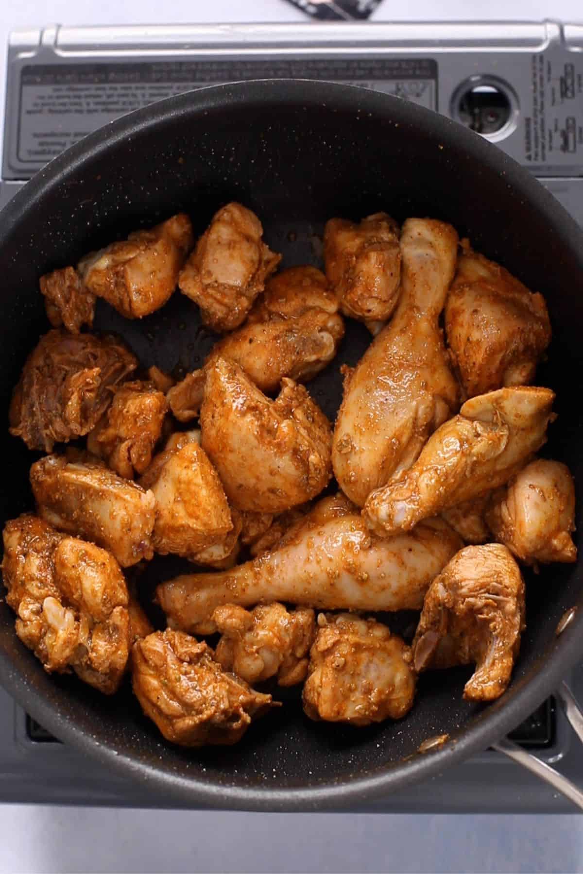 Seared chicken in a black cooking pot.