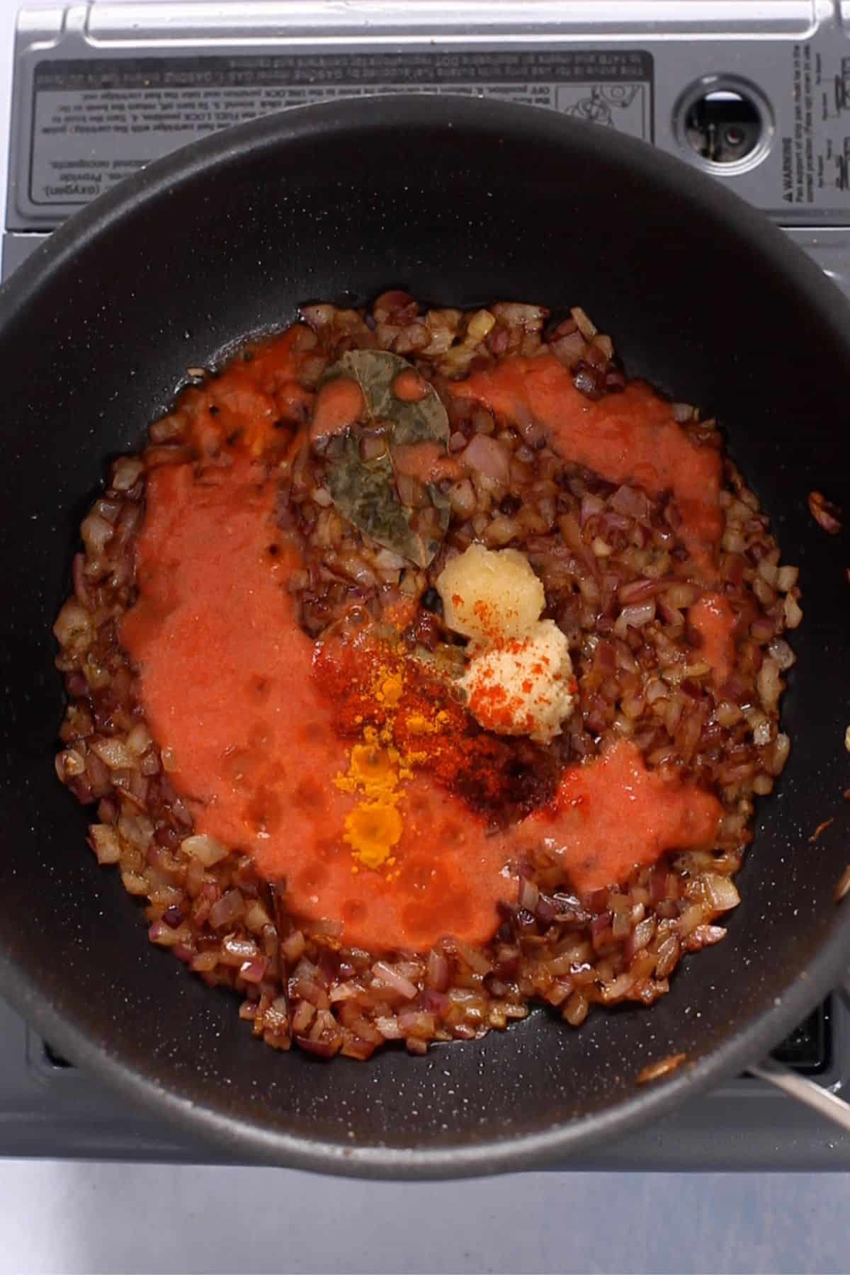 Ginger garlic and tomatoes are added next to the cooking pot.