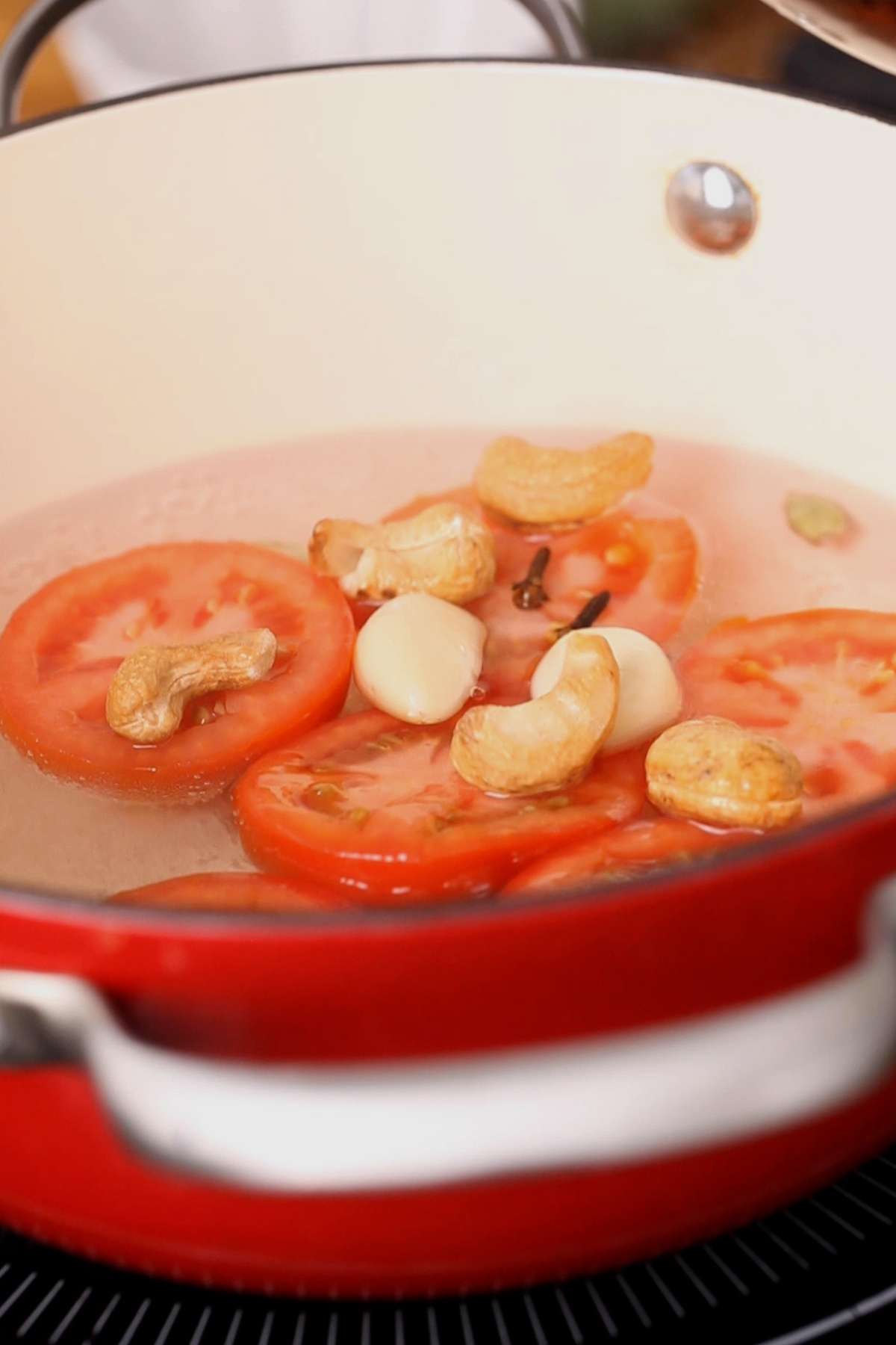 Boiling tomatoes, spices and nuts to make lababdar sauce.