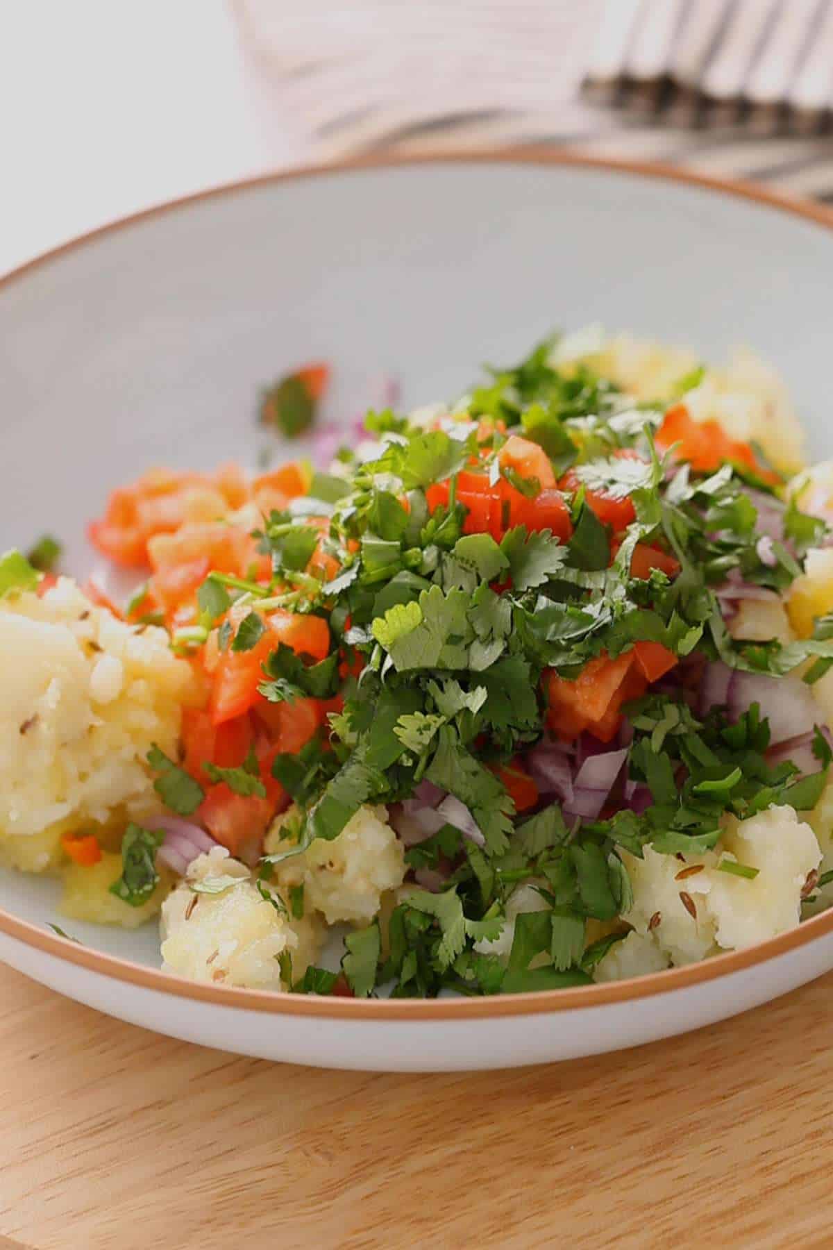 Add chopped onions, tomatoes and cilantro to potatoes.