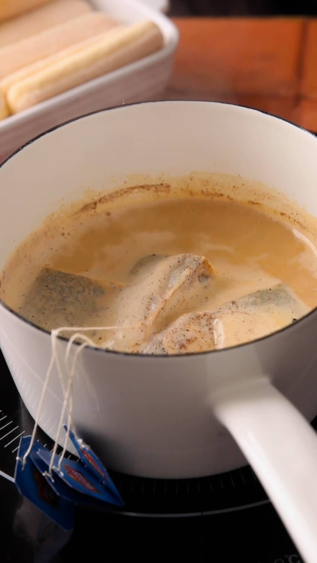 Brewing chai in a white enamel pot.