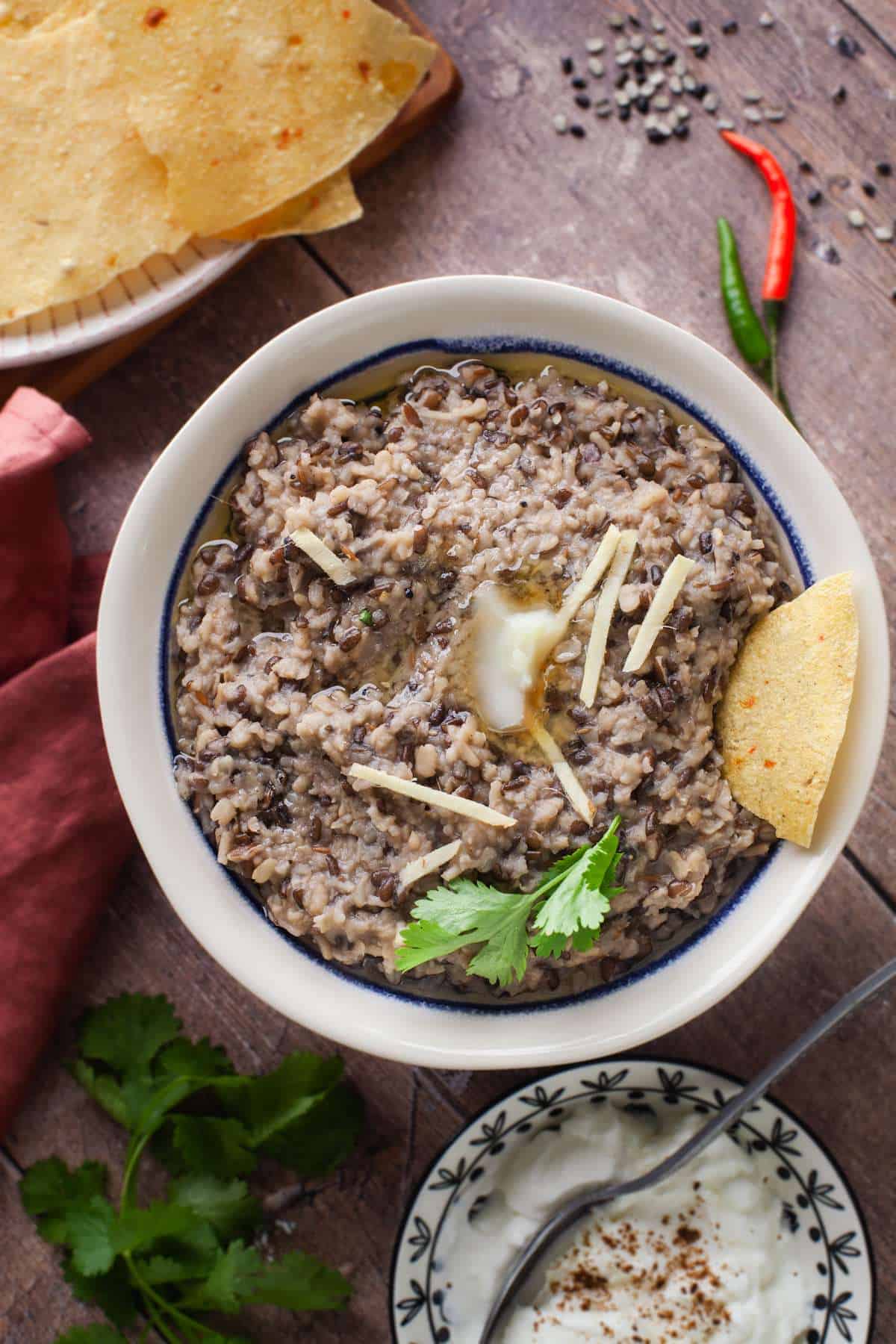 Urad Dal Khichdi served with a bowl of yogurt, papapdams and dollops of ghee.