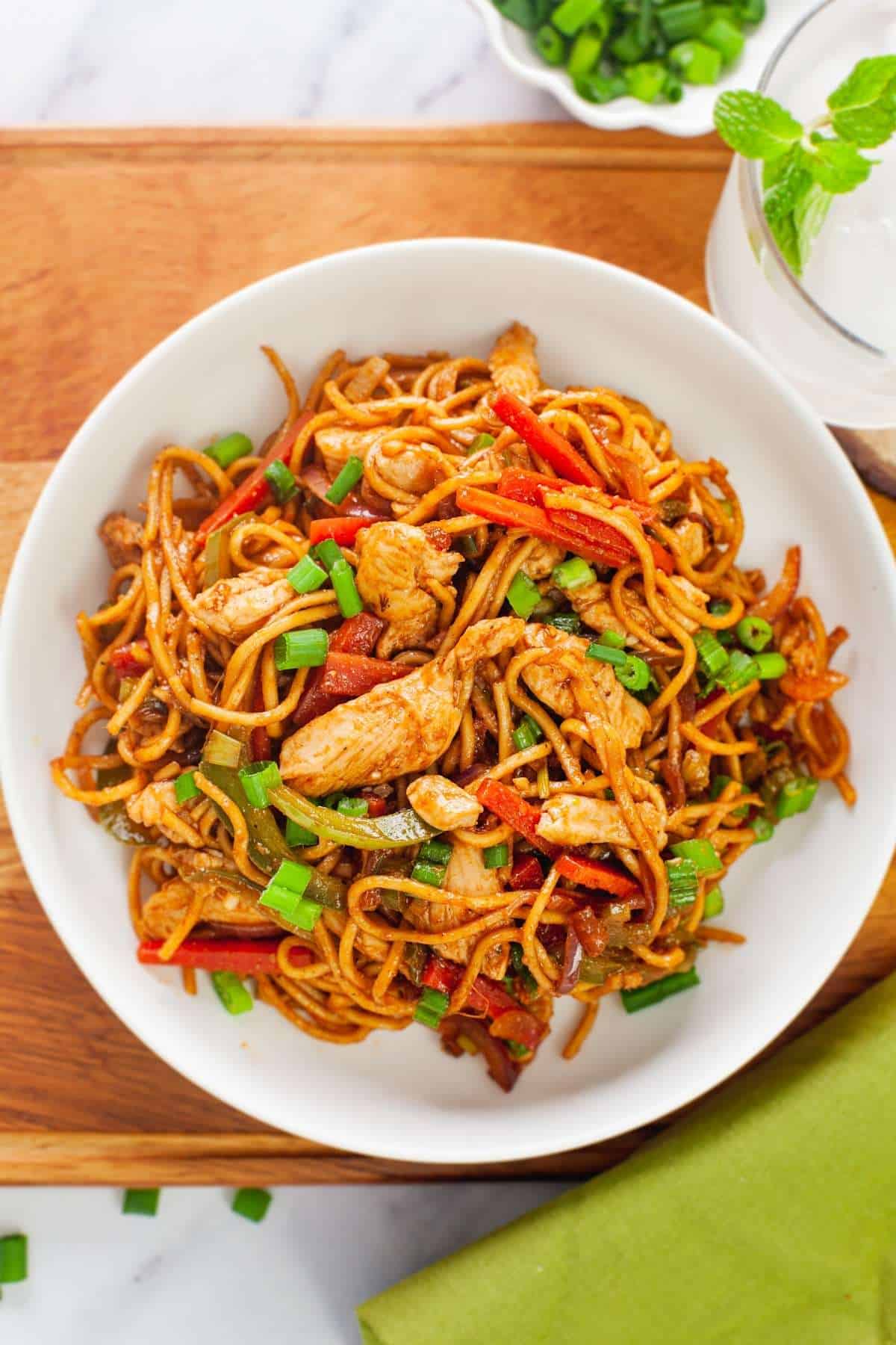 Overhead View of Chicken hakka noodles served with green scallions. 