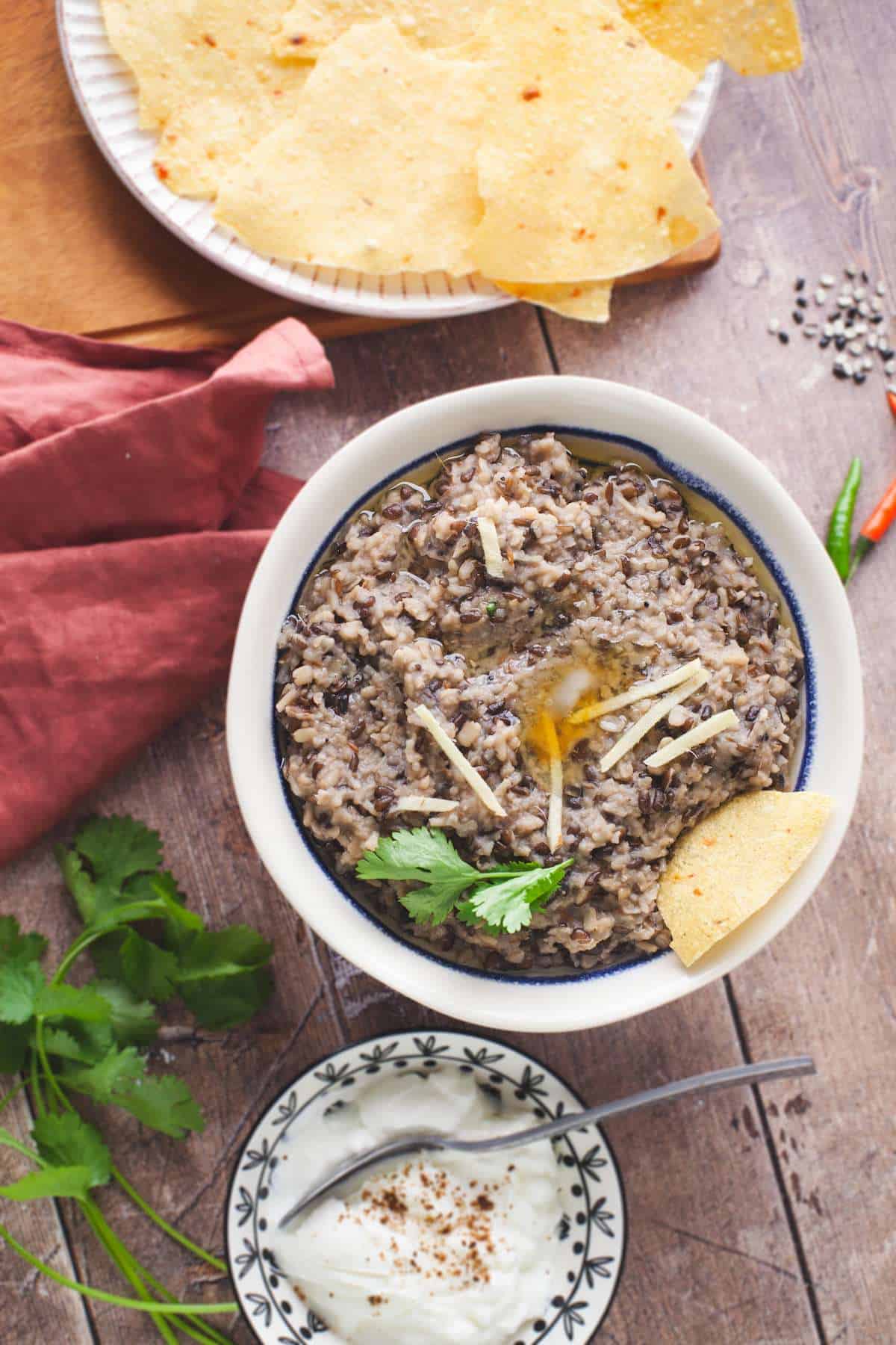 Urad Dal Khichdi served with a bowl of cumin yogurt, papad and of ghee.