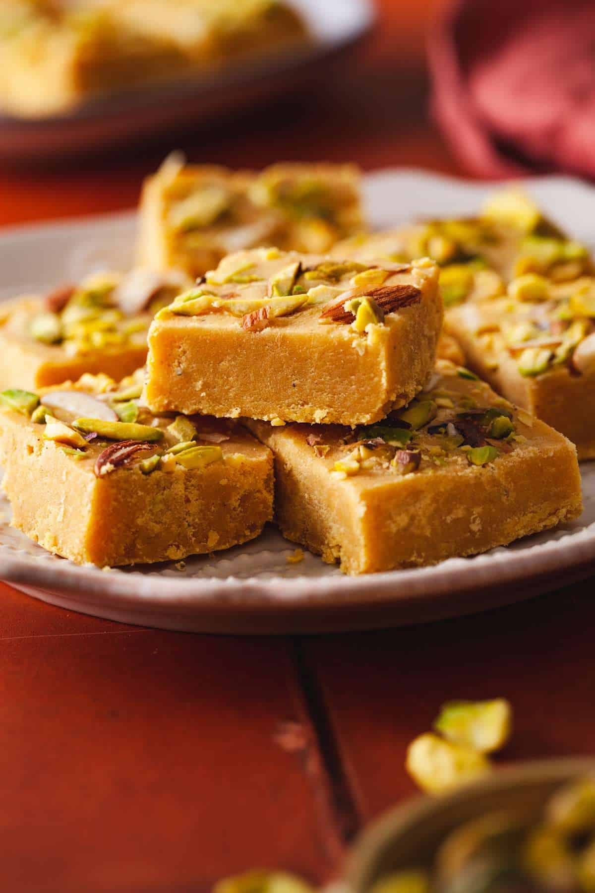 Close up of besan burfi squares stacked stacked on top of each other.  