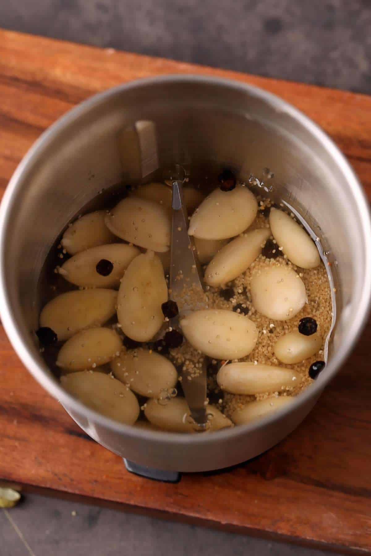 Peeled alomds and spices in a steel blender jar.
