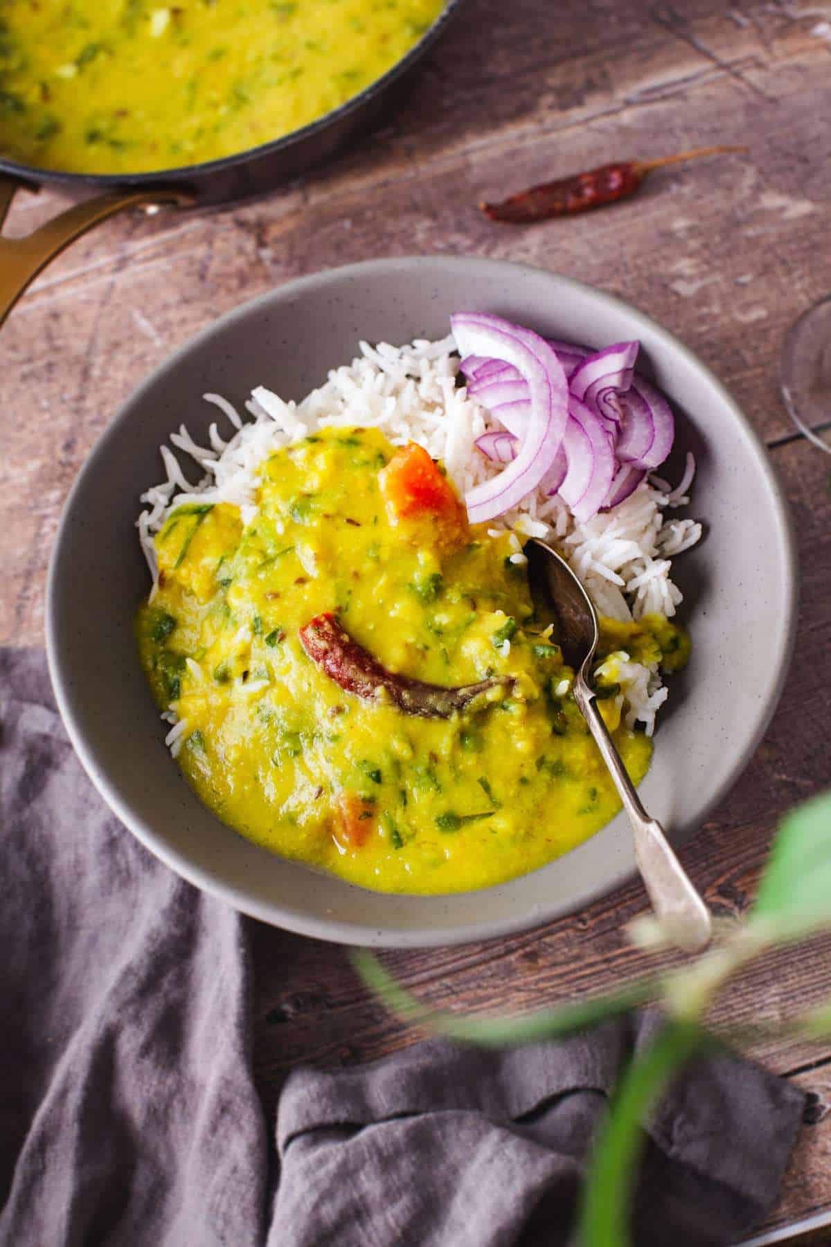 Methi Dal served with plain rice and sliced onions.