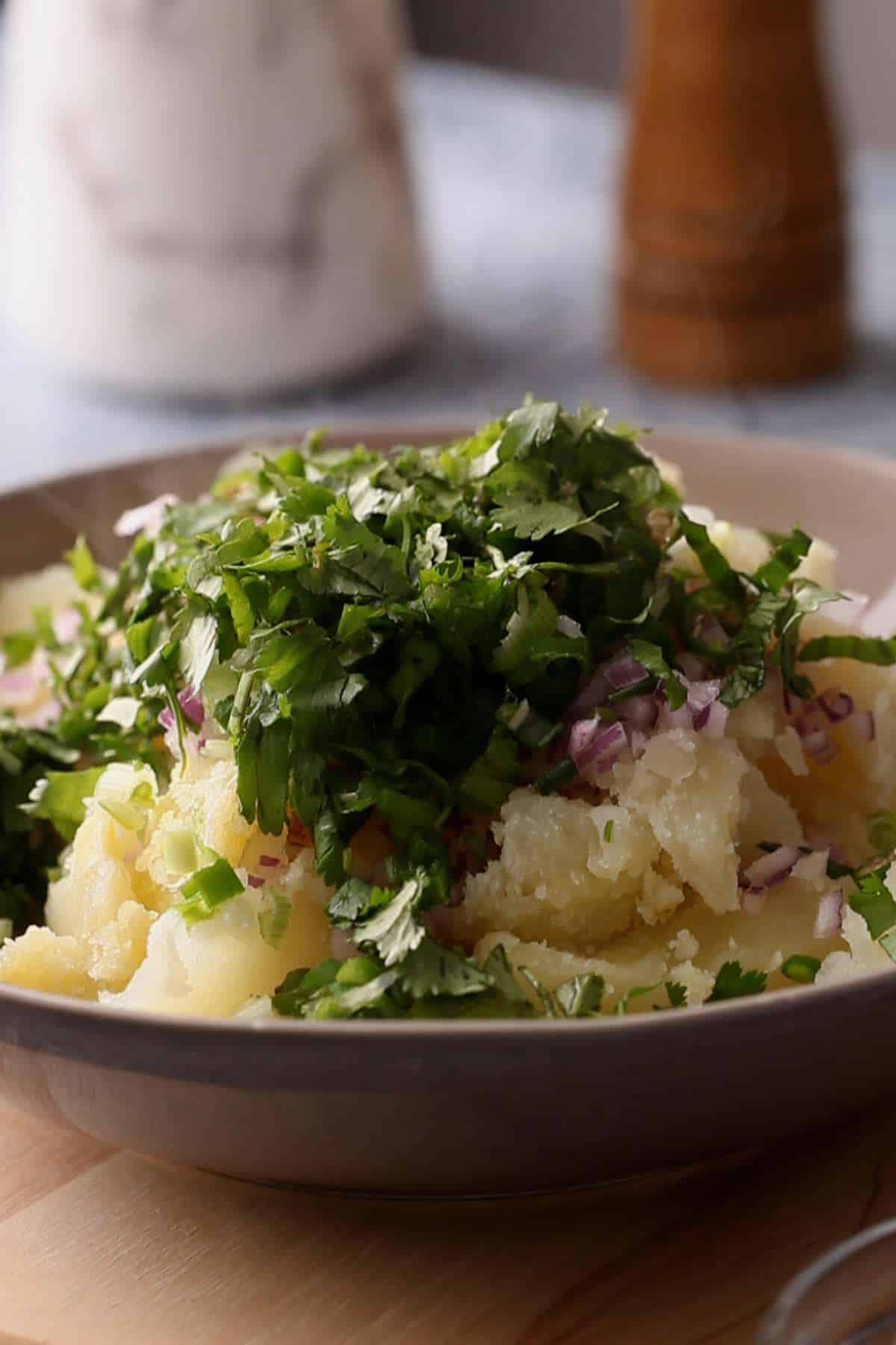 Adding onions, fresh herbs and spices to the potatoes.