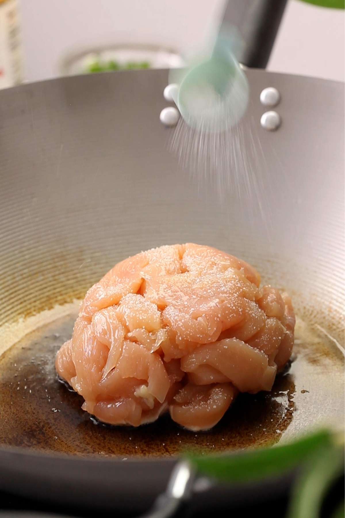 Add chicken to a heated wok and sprinkle salt. 