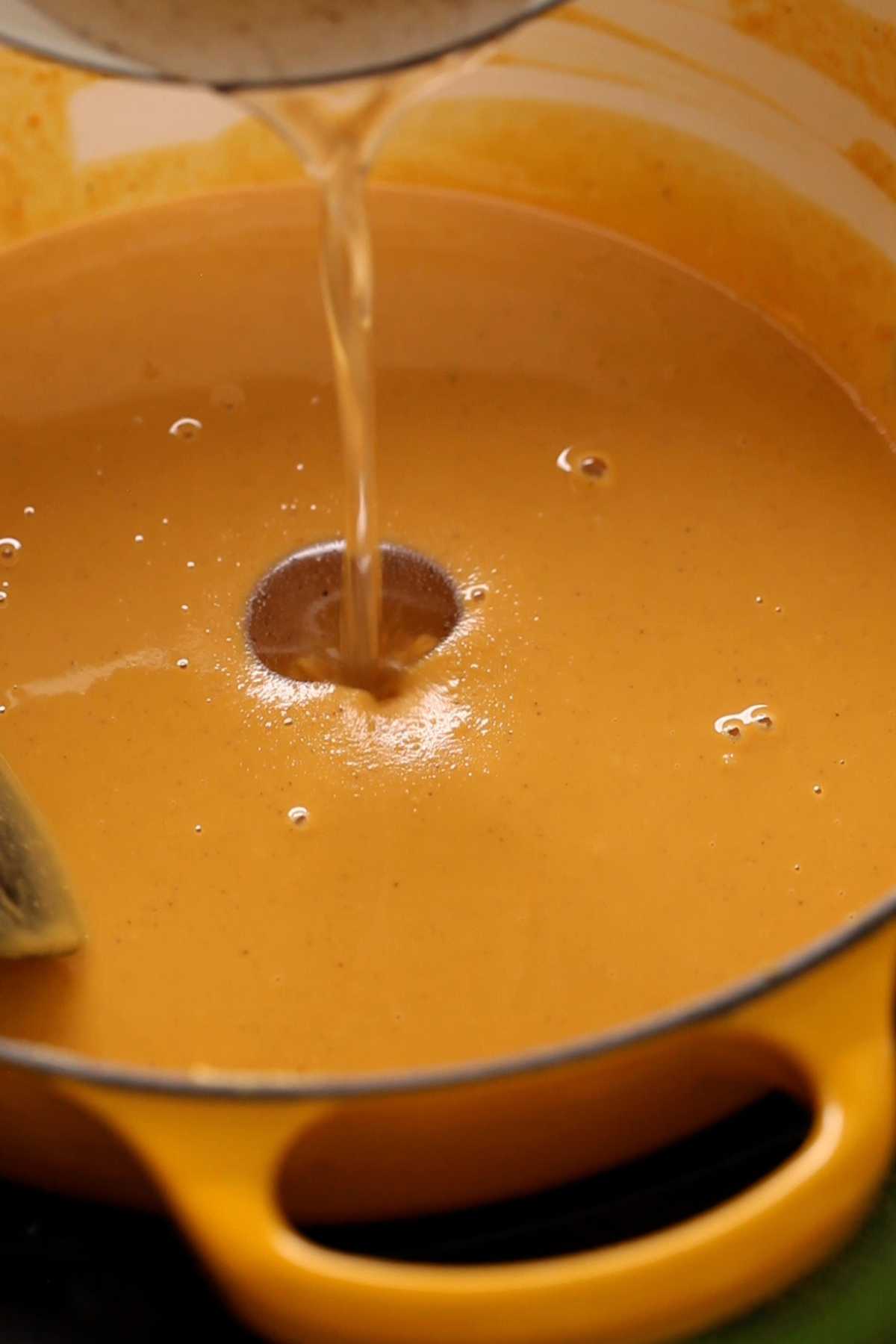 Adding sugar syrup to roasted besan. 