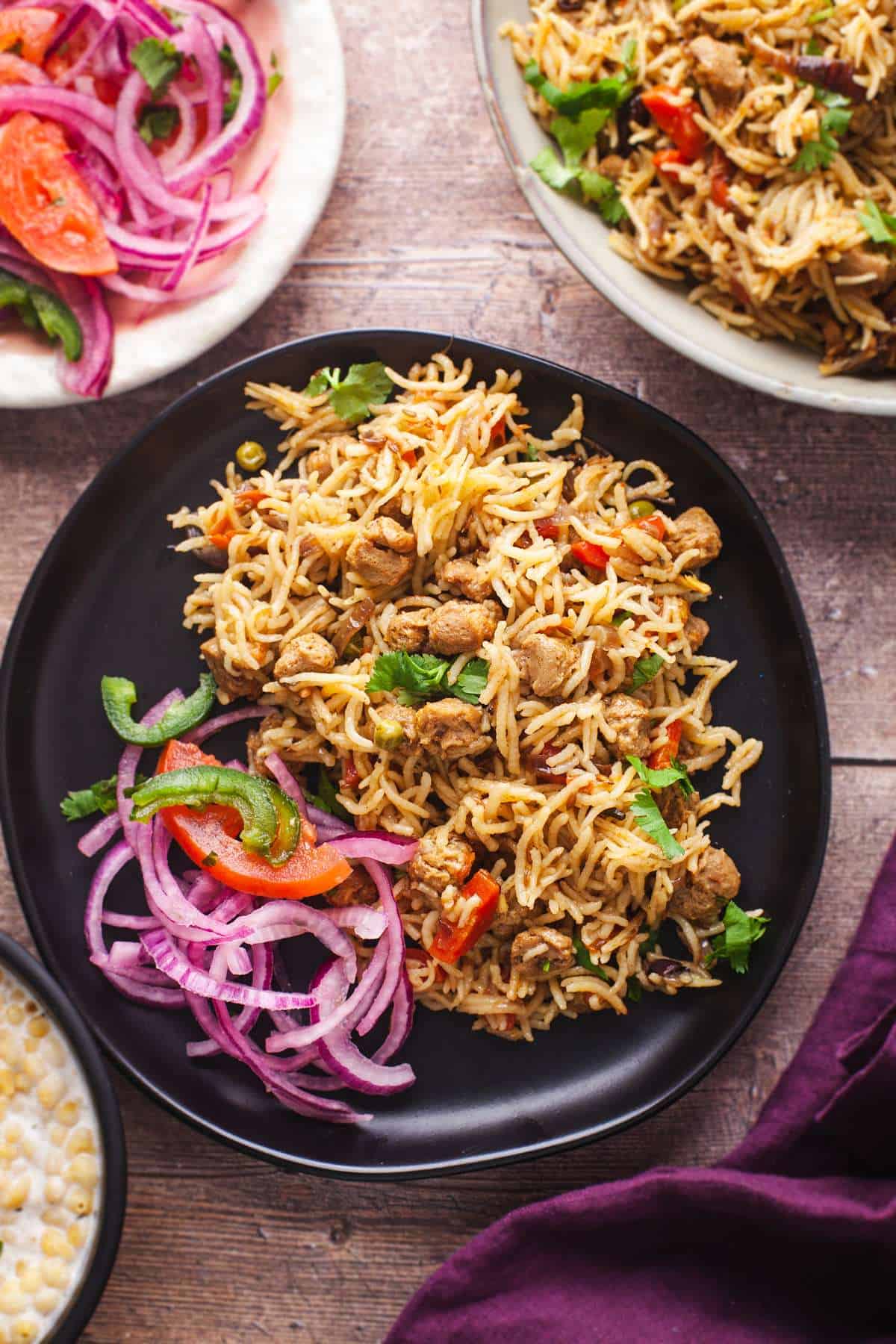 Soya Chunk Pulao in a black plate with onions on a rustic table background. 
