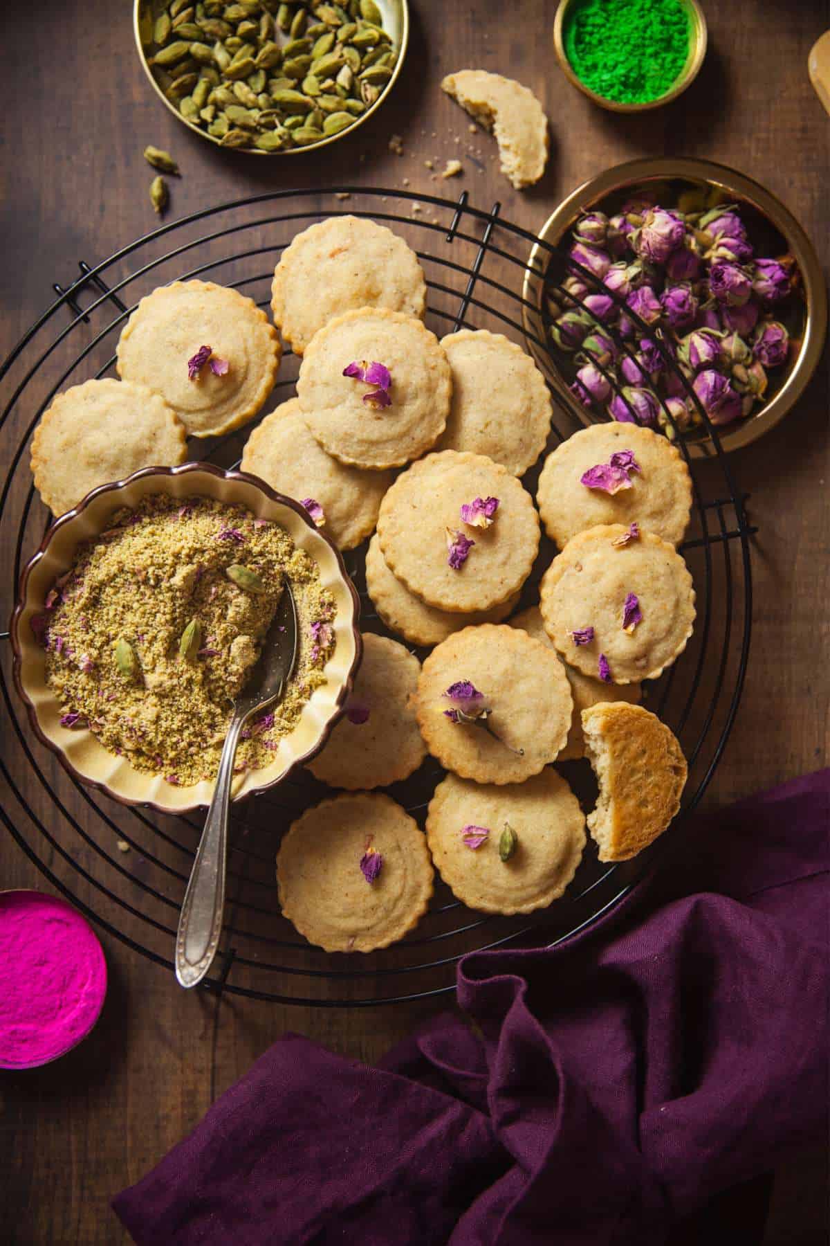 Thandai Cookies on a black wire rack decorated with dried rose petals.