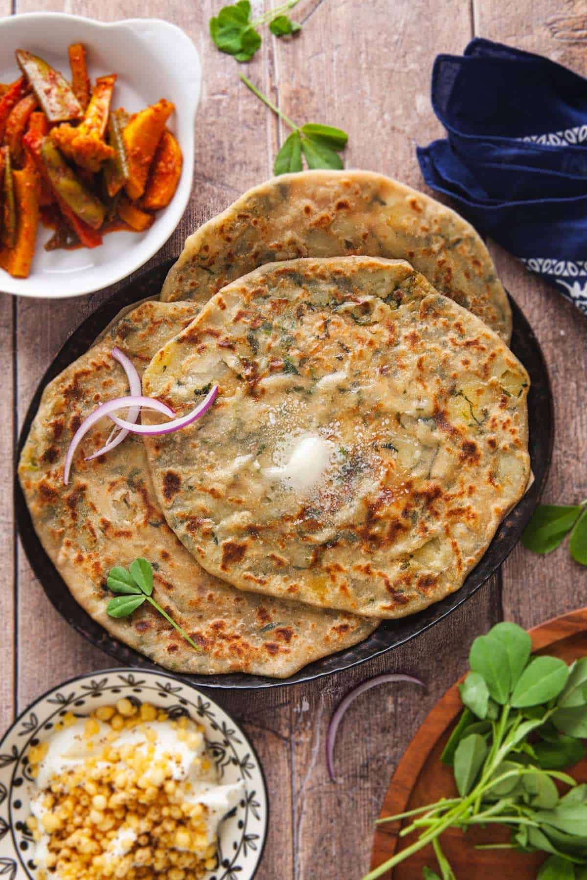 Aloo Methi Paratha served with spicy indian pickle, yogurt and butter on top. 