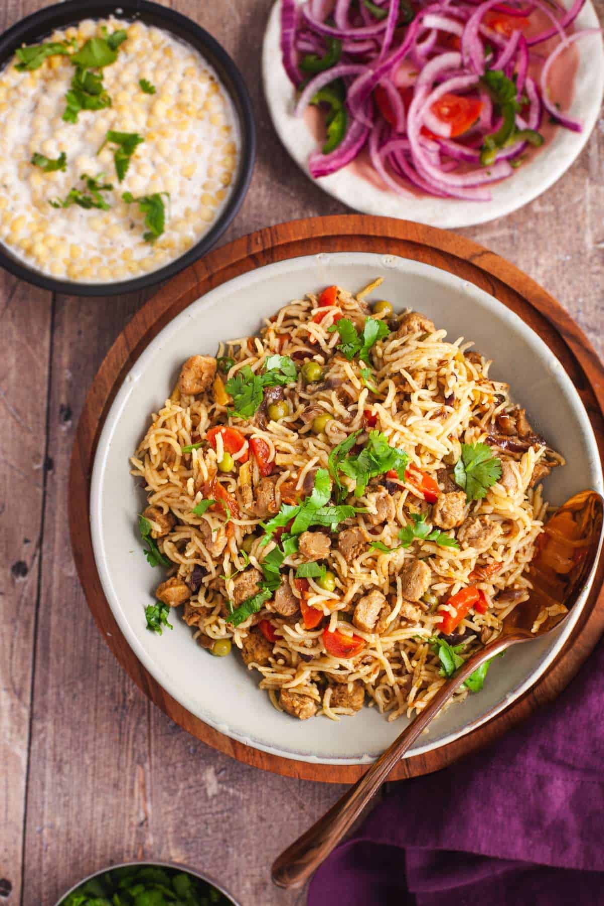 Nutrela Pulao in a grey bowl served with onion tomato salad and boondi raita.