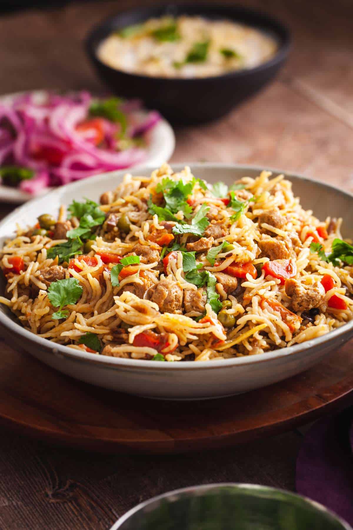 Side View of Soya Chunks Pulao with Salad and yogurt raita in background.