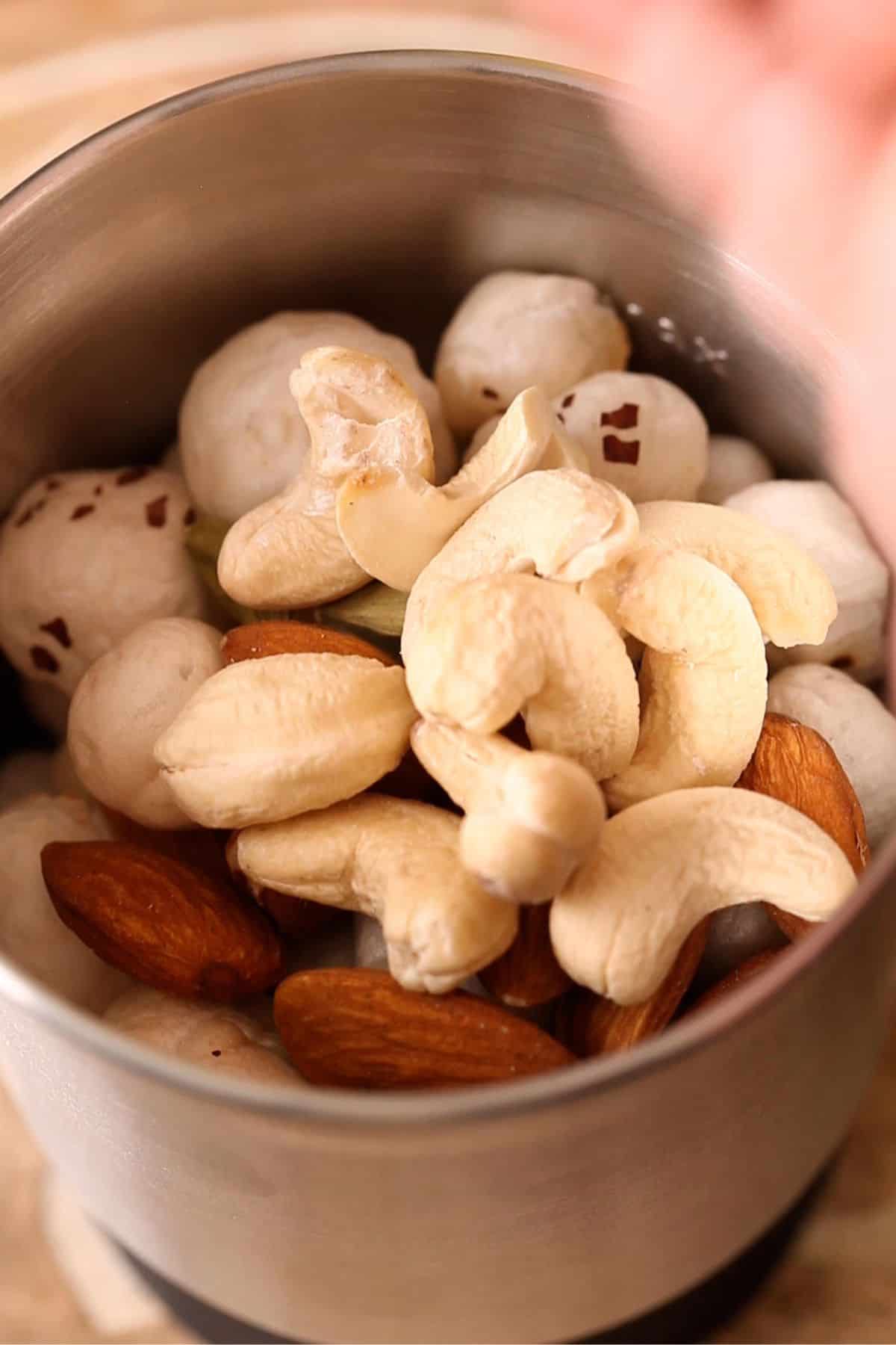 Toasted makhana and nuts are added to small blender jar. 