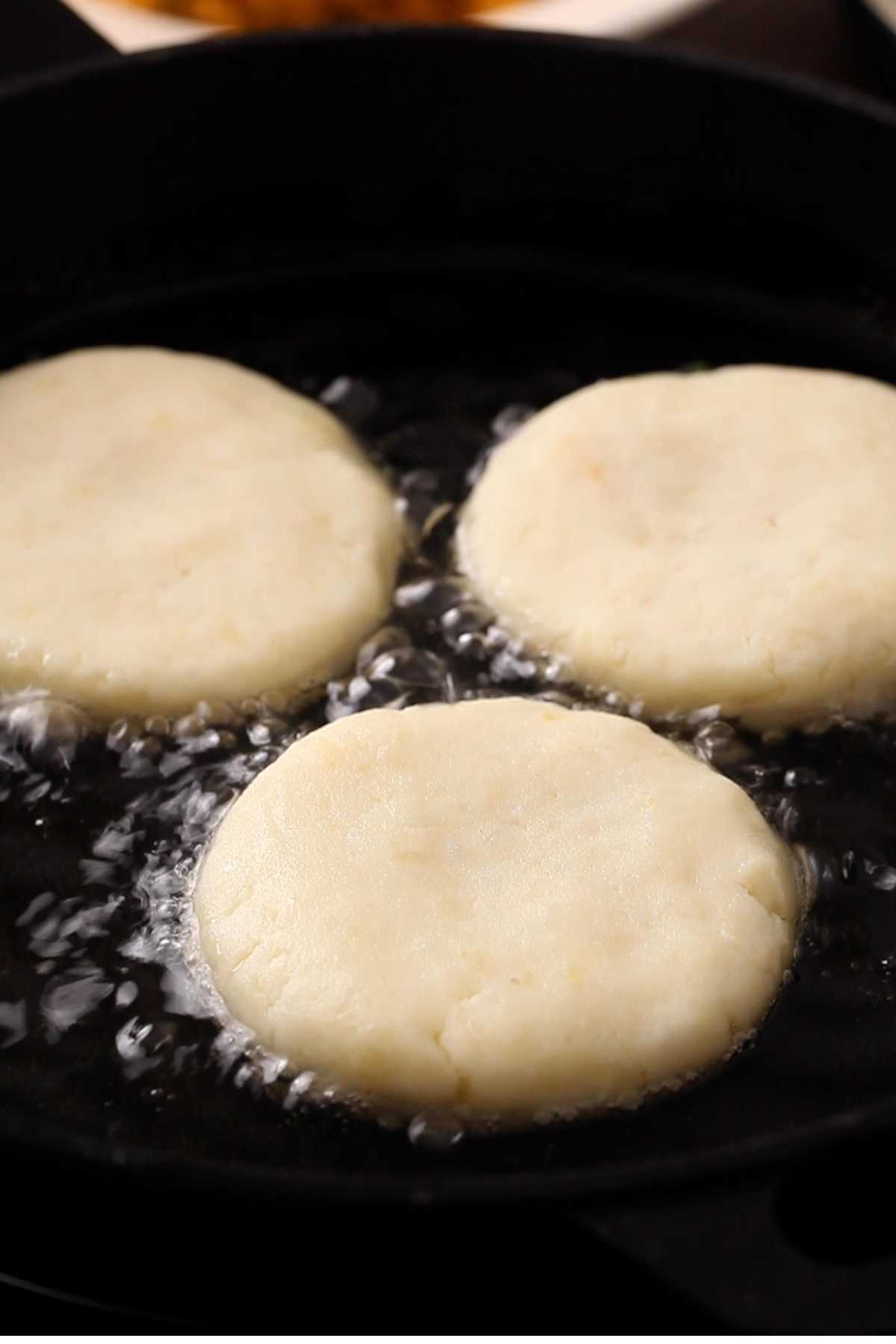 Shallow frying Aloo tikki in a cast iron pan.