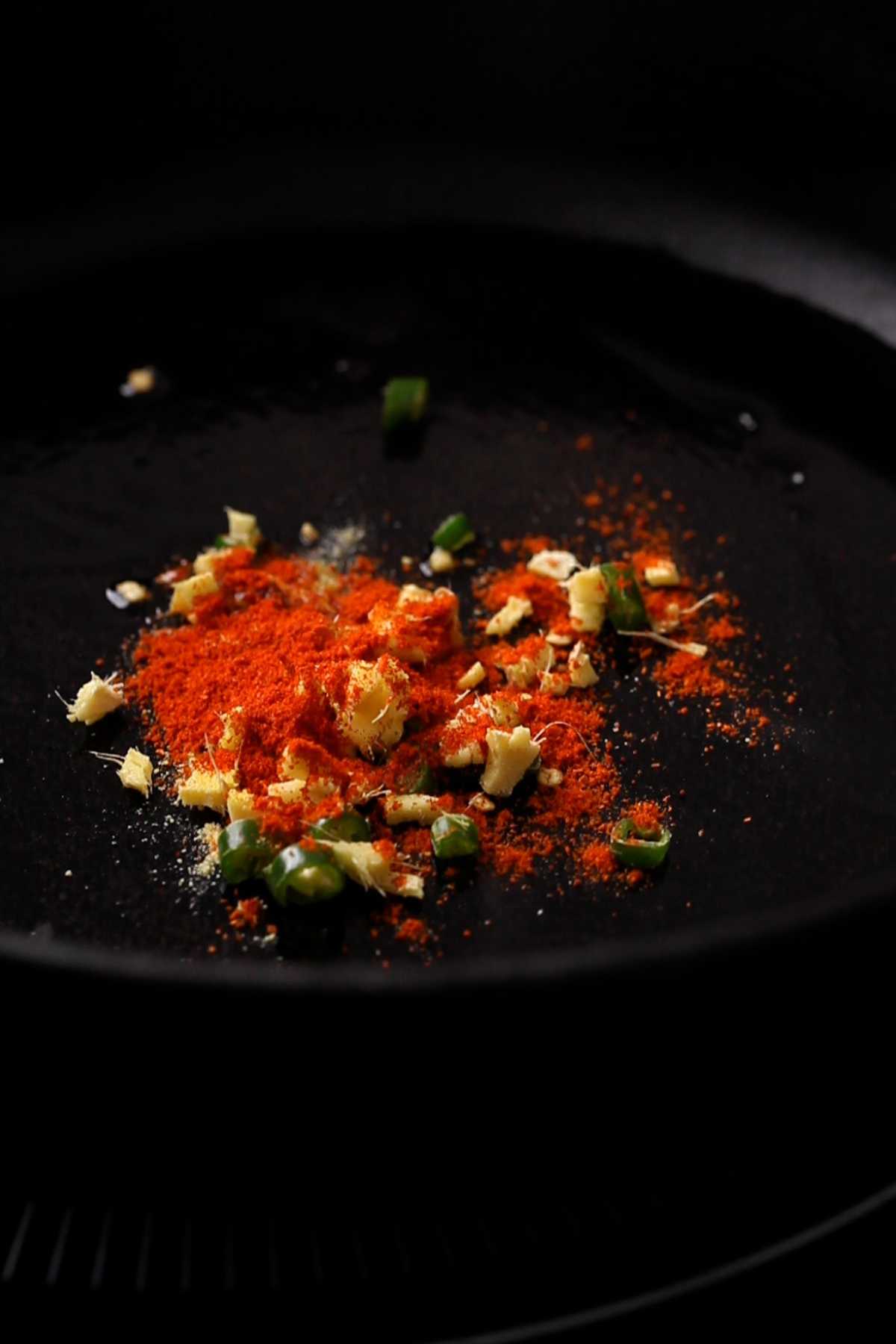 Tempering chana lentils with spices in a cast iron pan.
