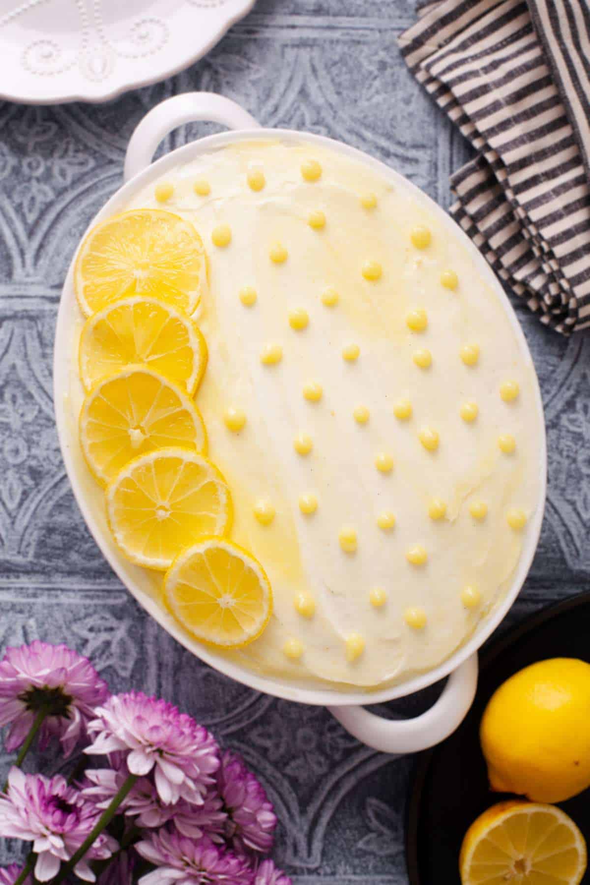 Lemon Tiramisu decorated with lemon slices and eggless lemon curd in an oval dish.