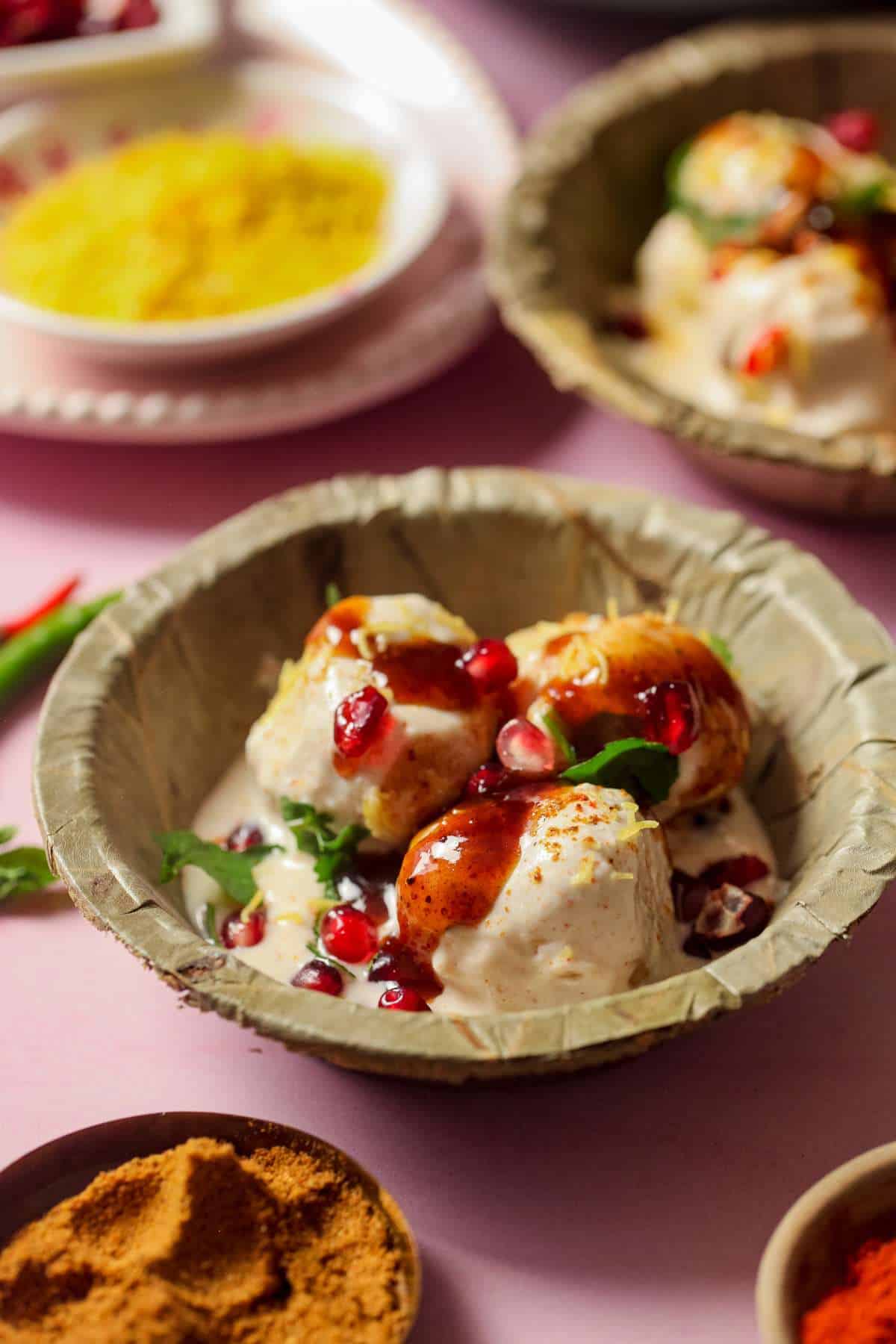 Side shot of dahi vada with sweet tamarind chutney dripping.