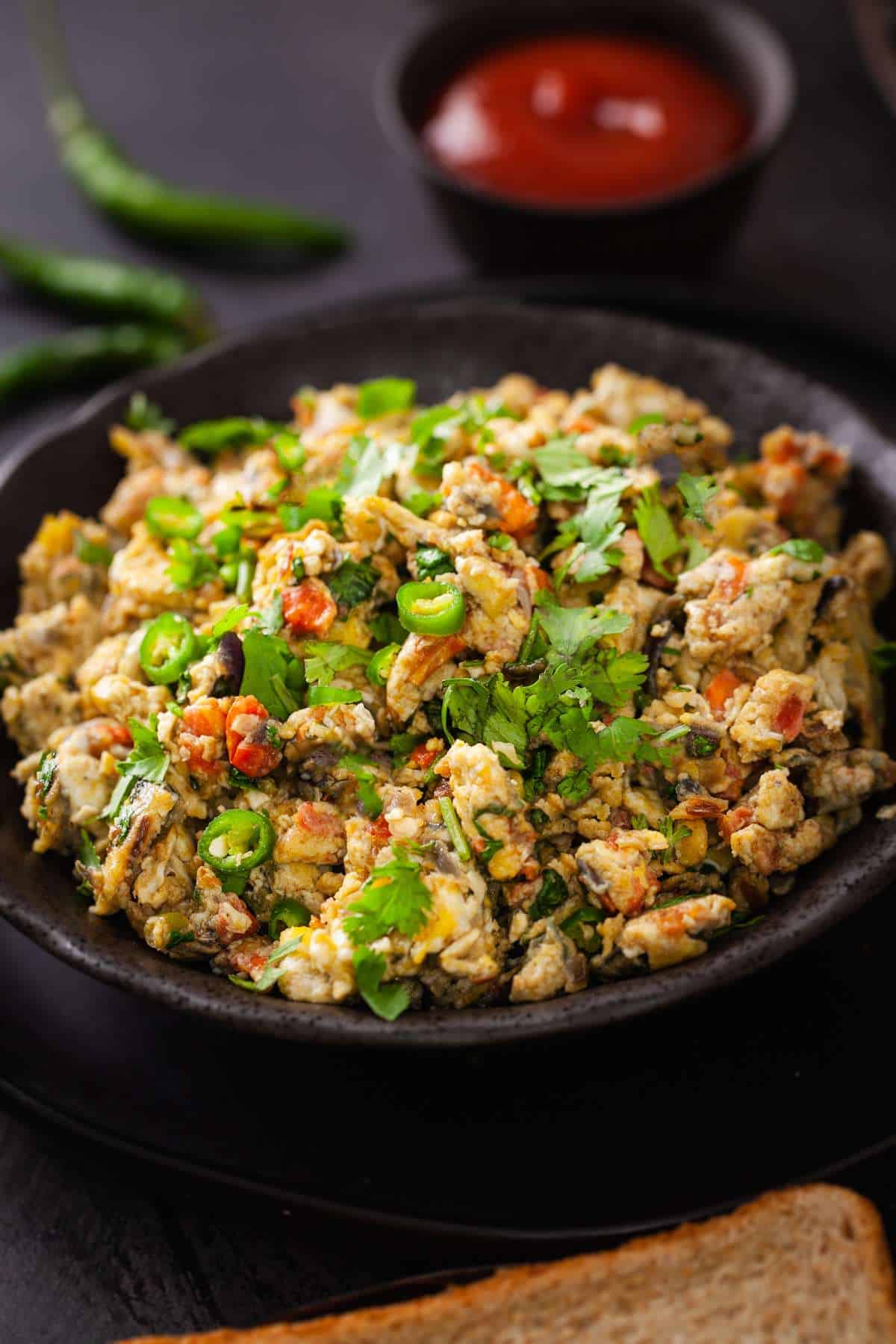Side View of spiced instant style scrambled eggs plated in a shallow black bowl.