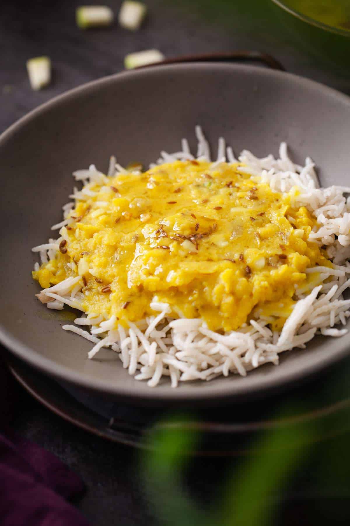 A grey bowl of mango dal served over steamed basmati rice and topped with ghee.