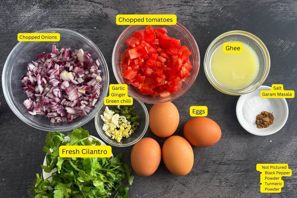 Ingredients needed to make egg bhurji placed on a black board.