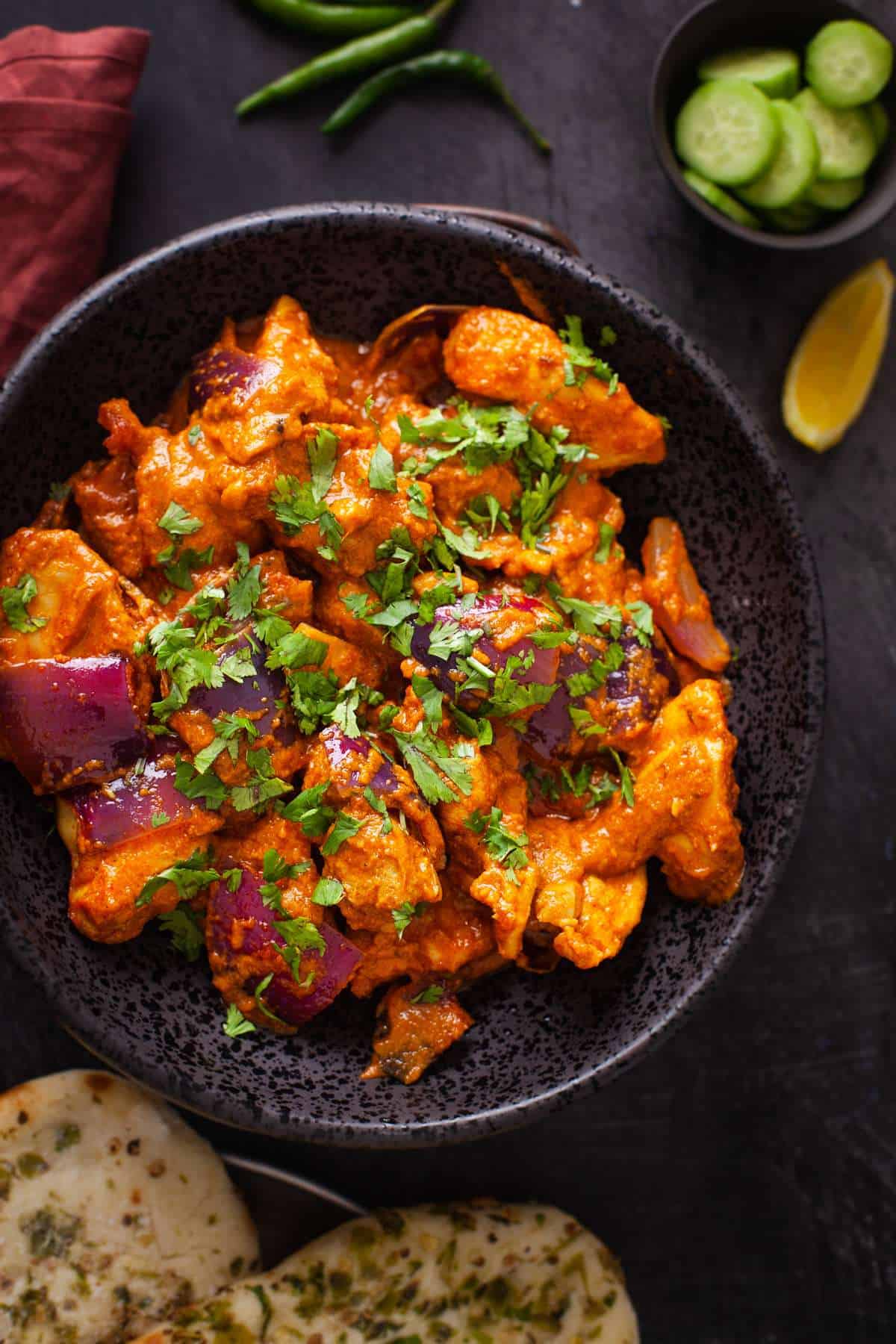 Close up image of chicken do pyaza served in a black bowl.