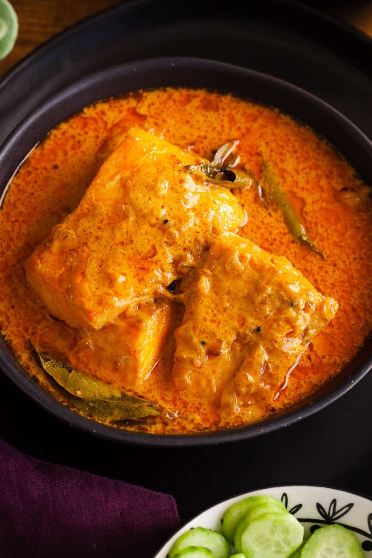 Closeup shot of indian salmon curry served in a black bowl. 