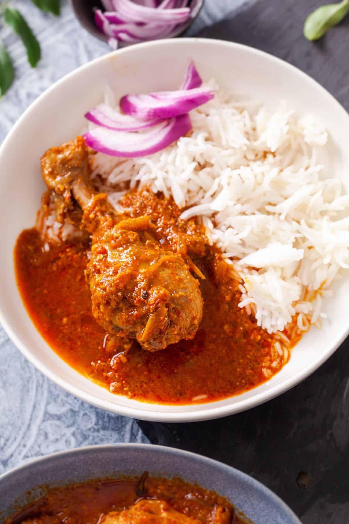 Chettinad chicken curry served with rice in a blue bowl.
