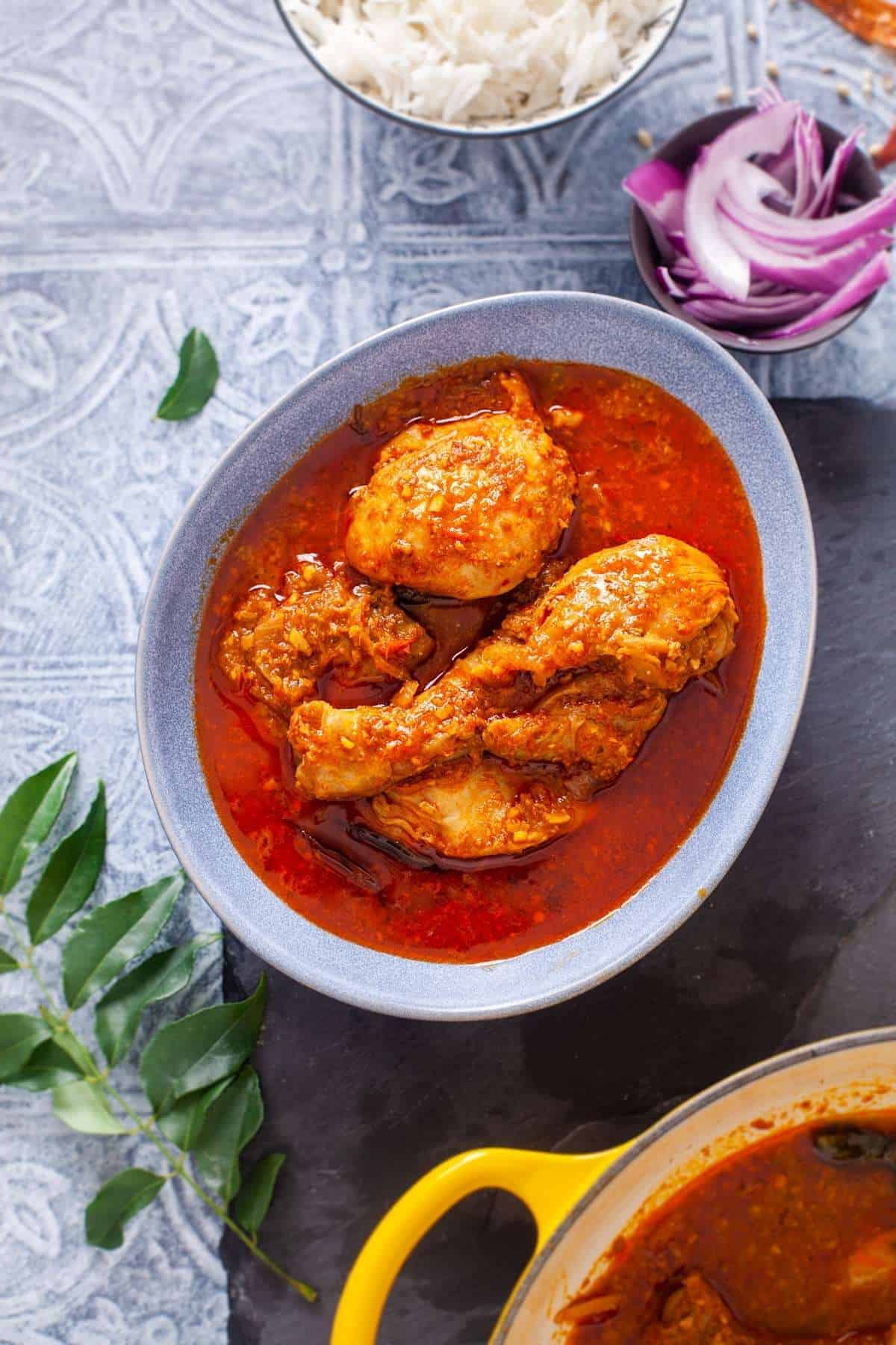 Chettinad Chicken served in an egg shaped blue bowl with steamed rice. 