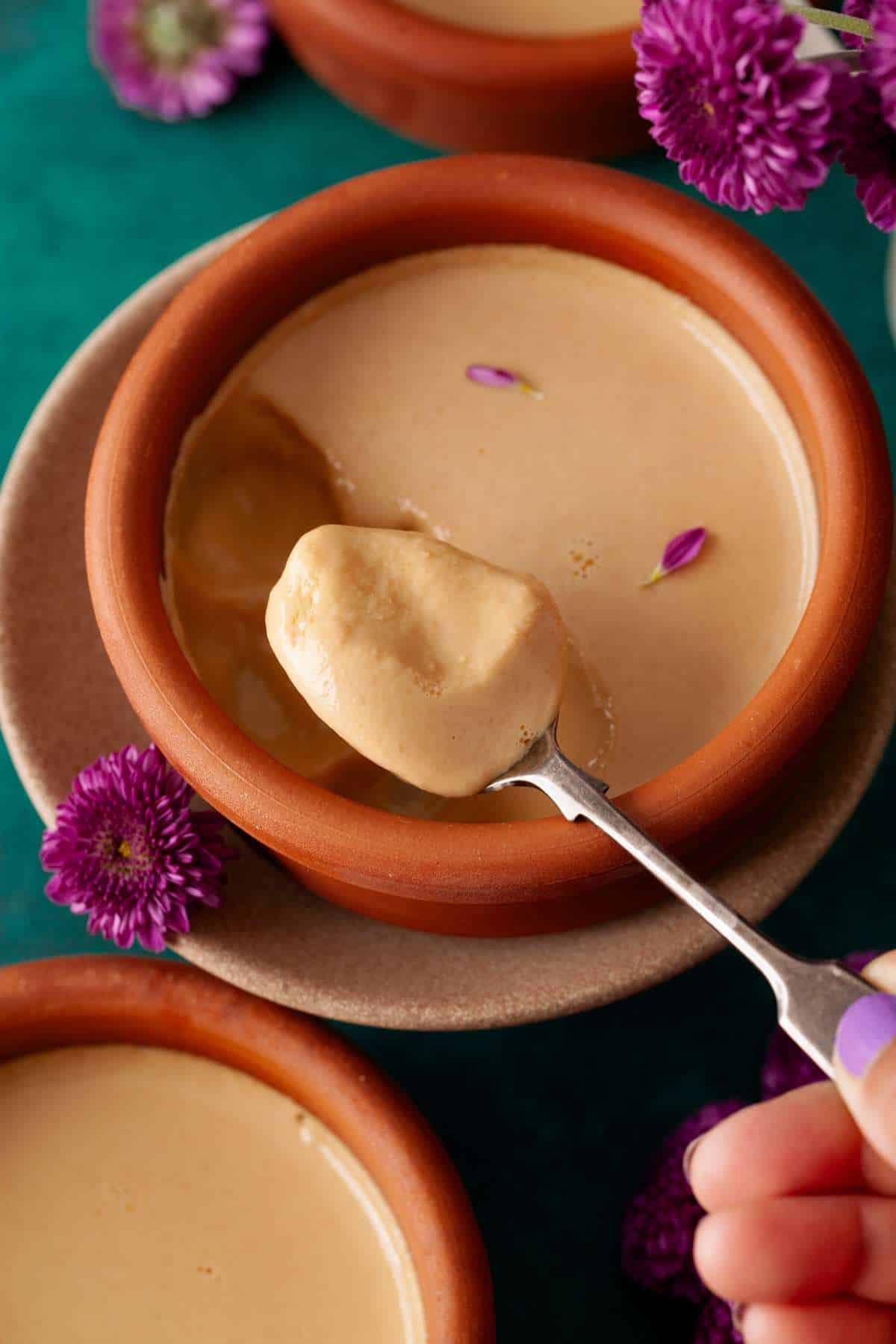 Scooping mishti doi using a spoon.