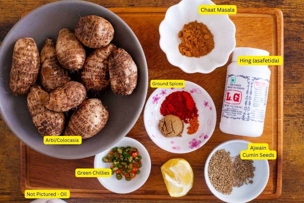 Ingredients needed to make arbi fry on a wooden board.
