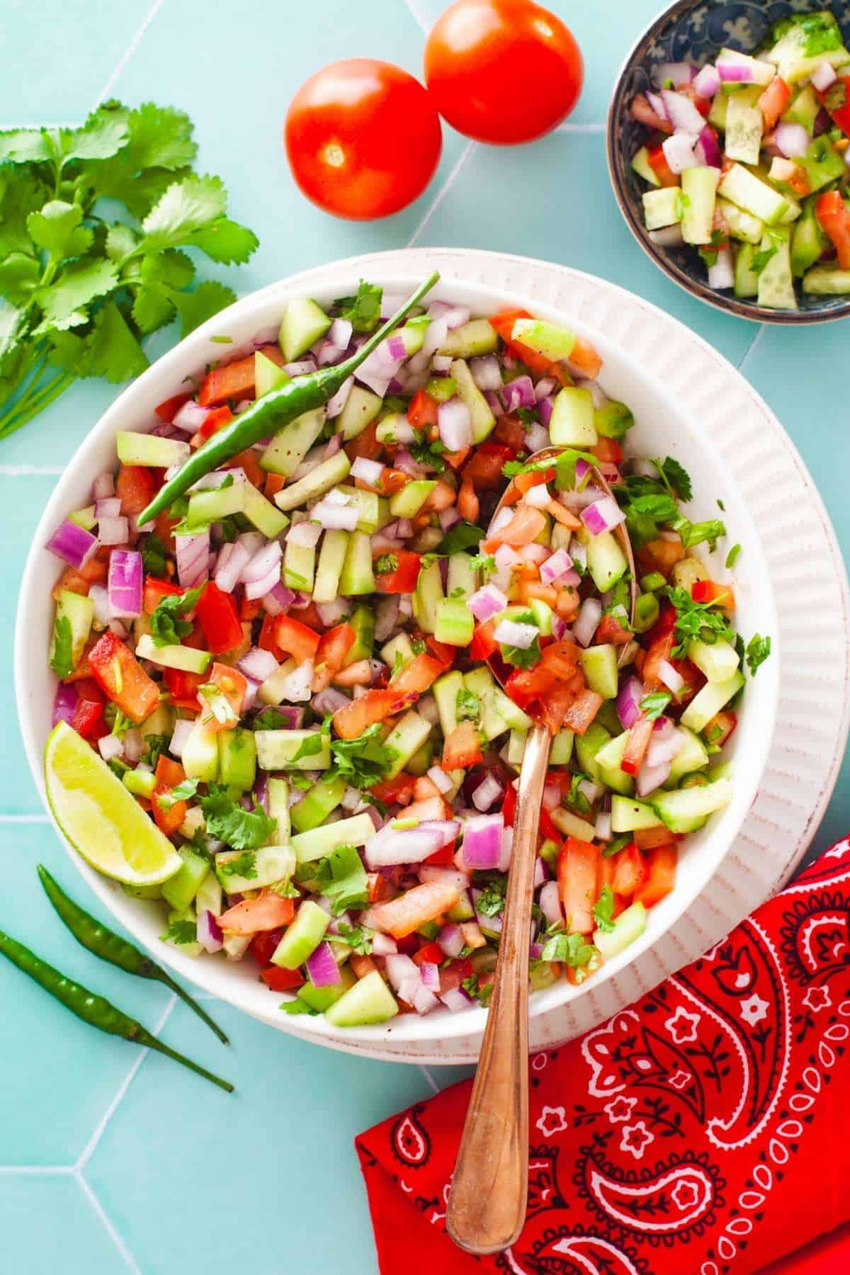 Kachumber salad in a white bowl with spoon. 
