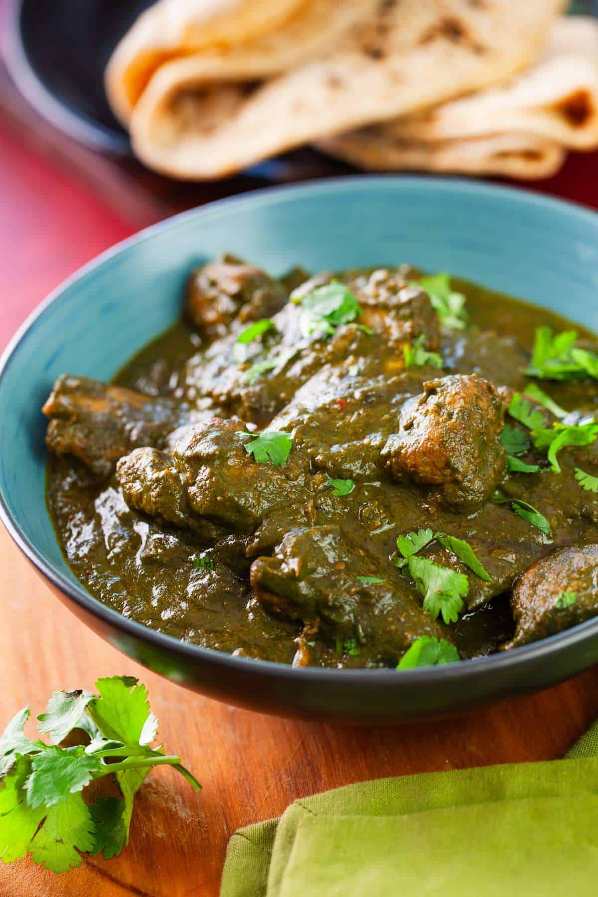 Side view of indian chicken spinach curry with rotis.