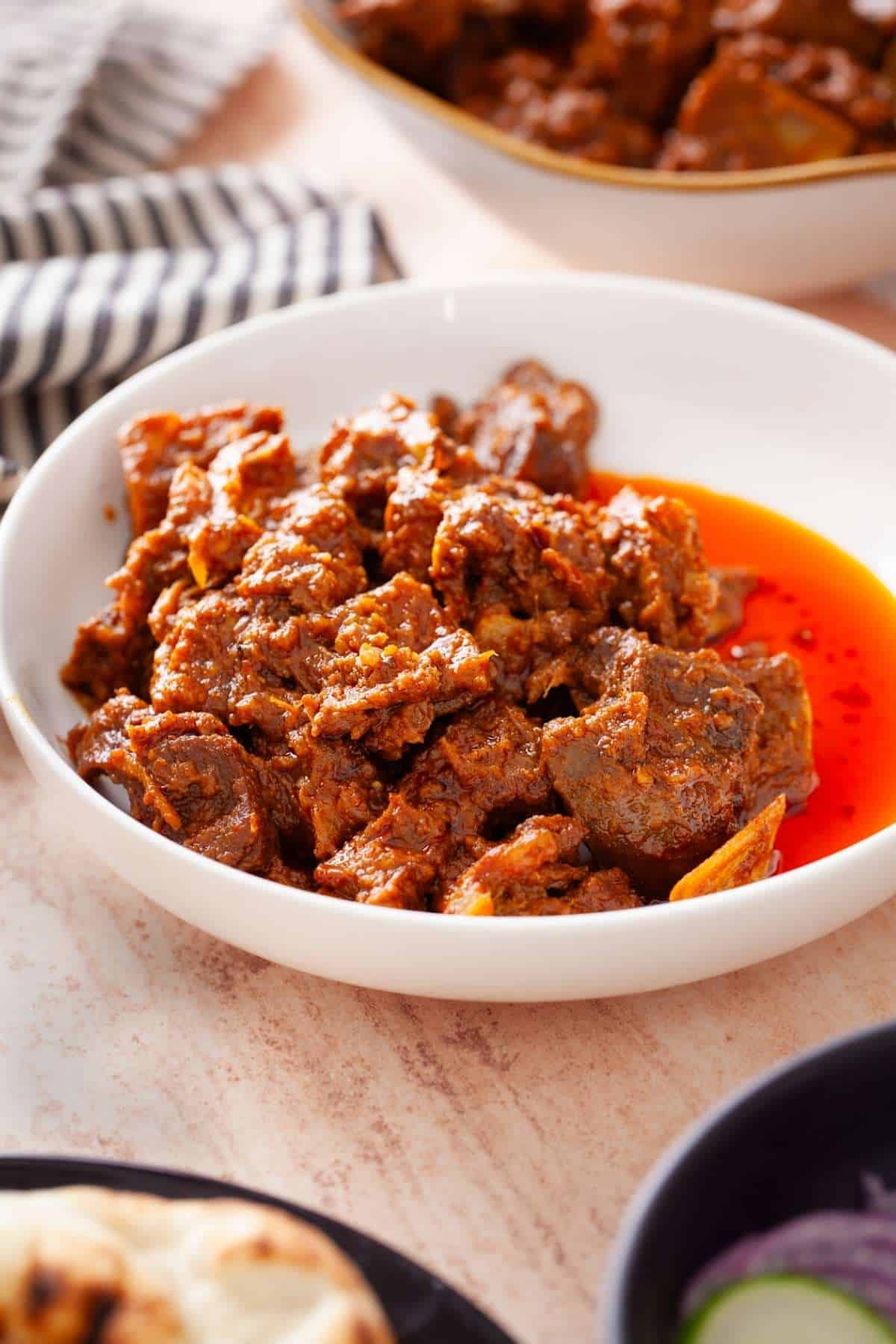 Side shot of bhuna gosht in a white bowl. 