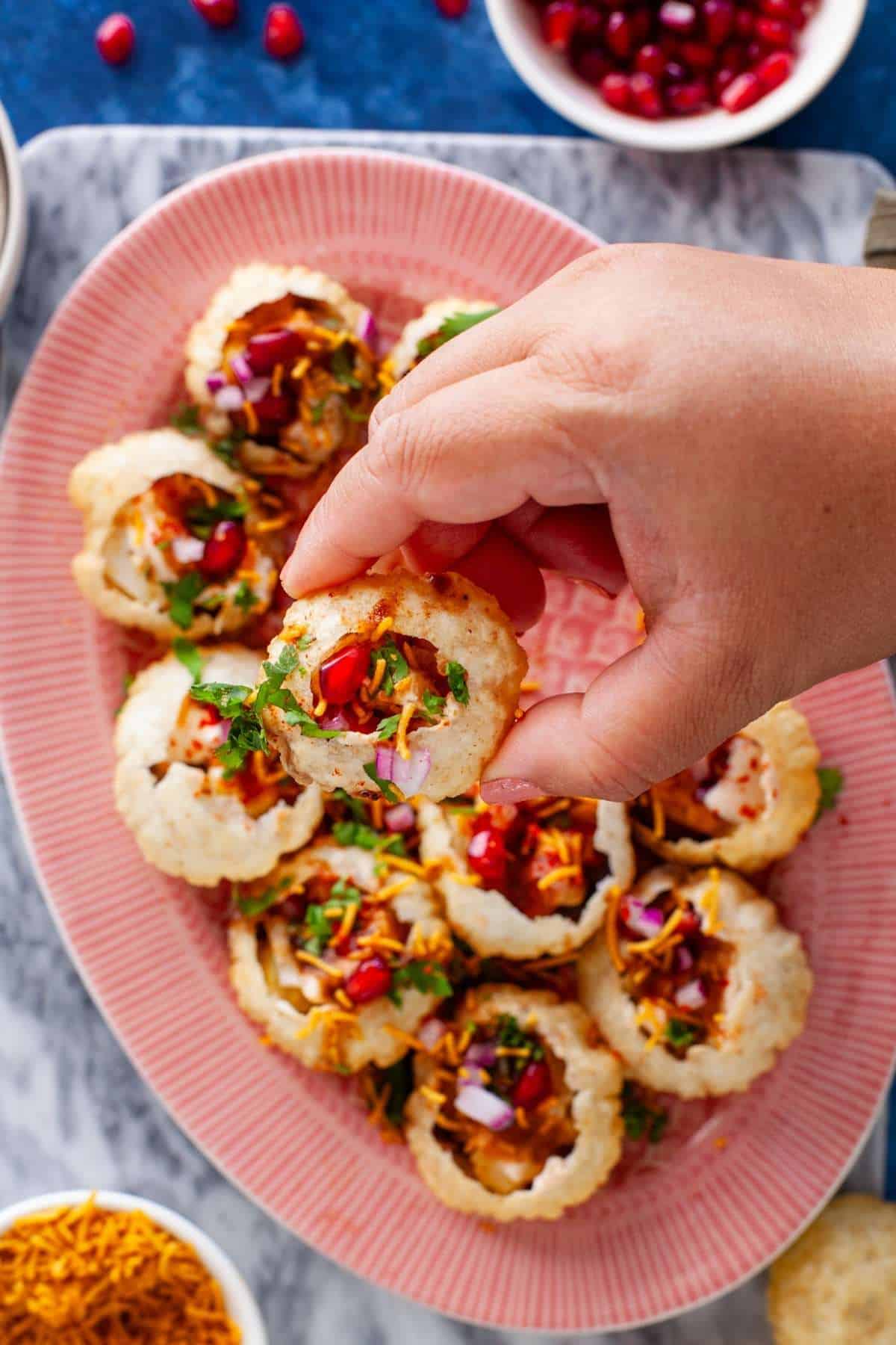 Hand holding a dahi filled poori chaat.