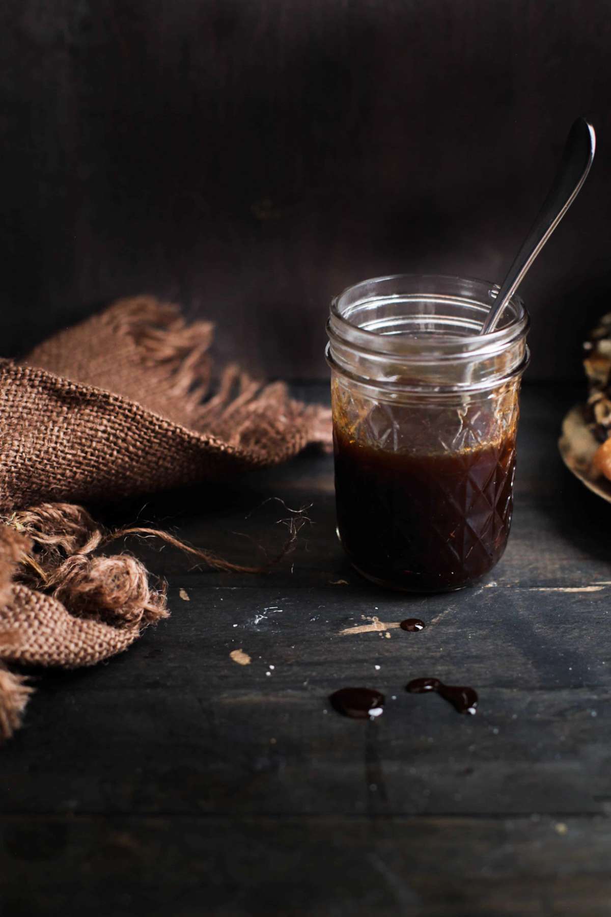 Tamarind chutney in a glass jar in a dark moody image. 