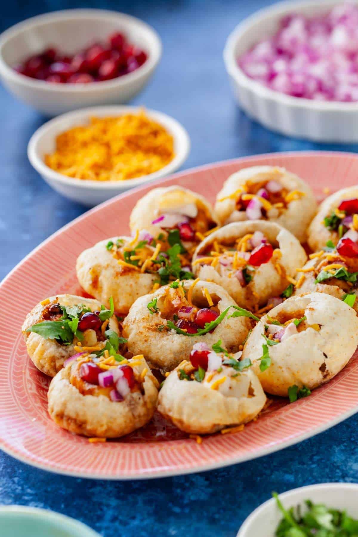Side view image of Dahi Puri on a pink platter.
