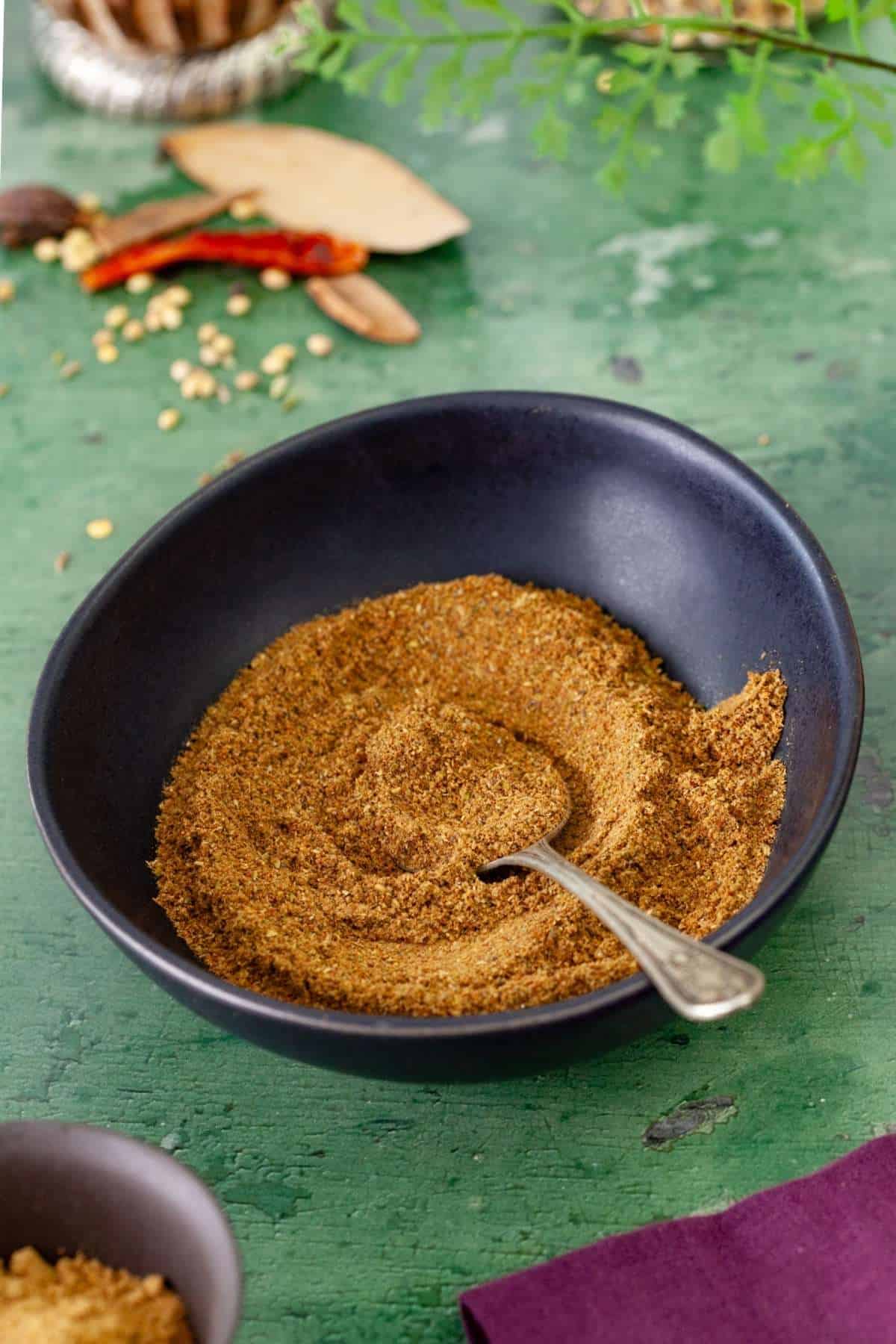 Side shot of garam masala in a black bowl.