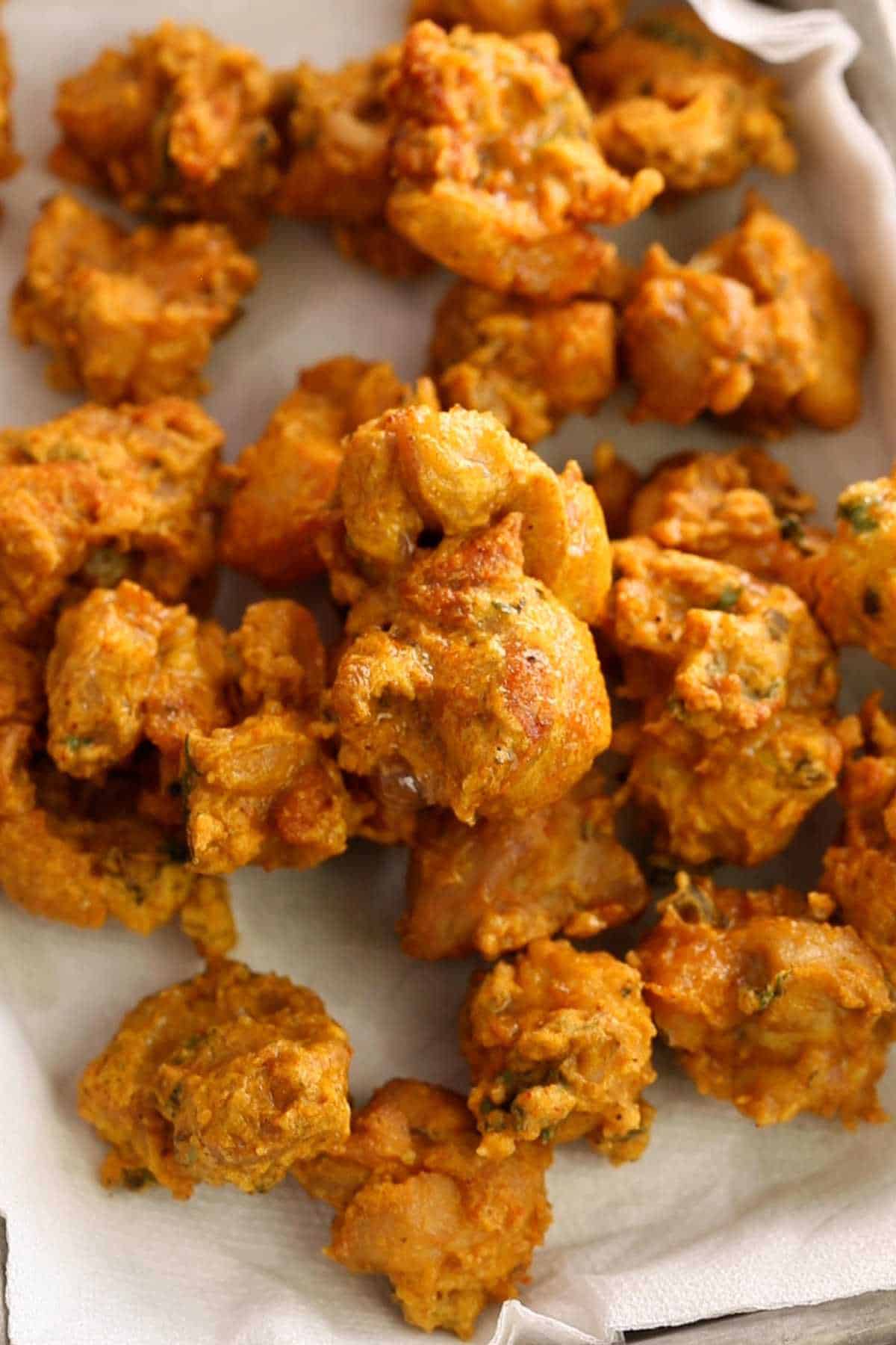 Crispy chicken pakoras in a paper towel lined tray.