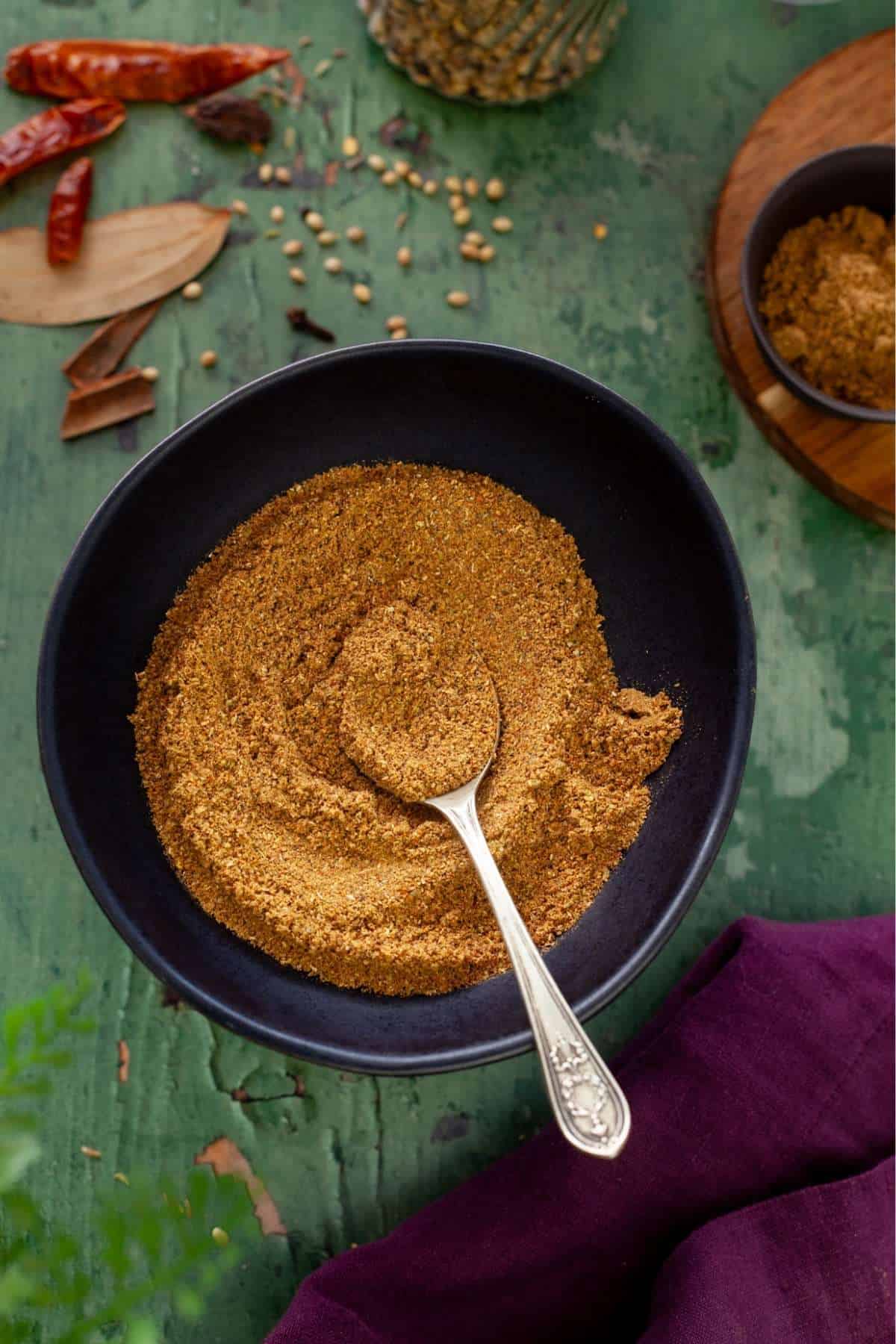 Garam Masala in a black bowl placed on a green background.