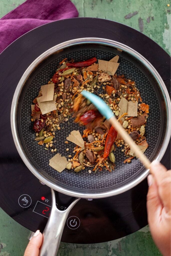 Stirring whole spices while roasting.