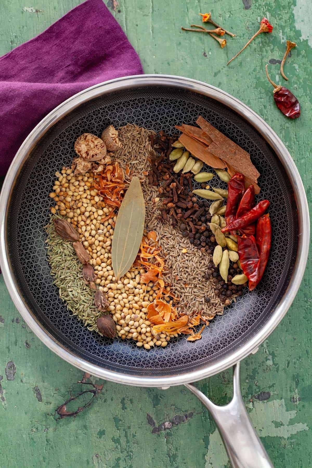 Whole spices in a black pan.