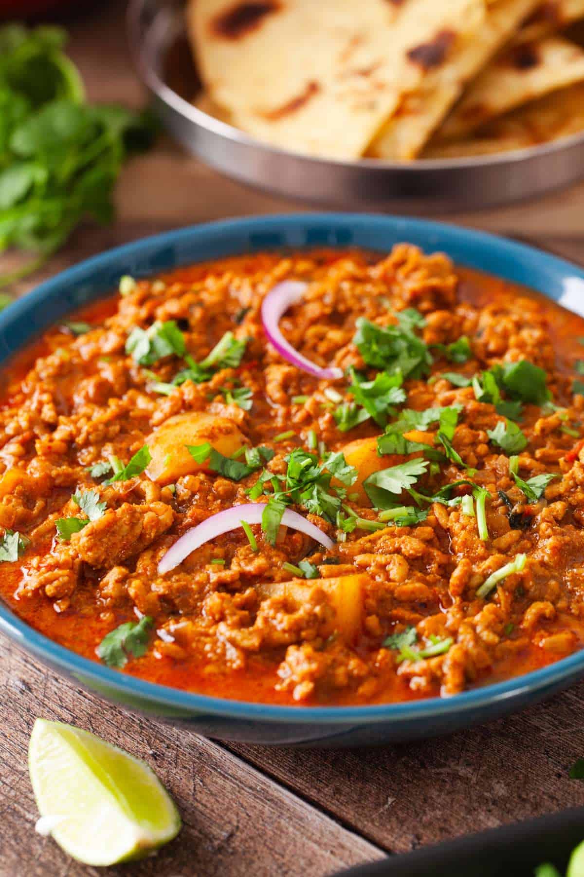 Side view of chicken keema with roti in background.